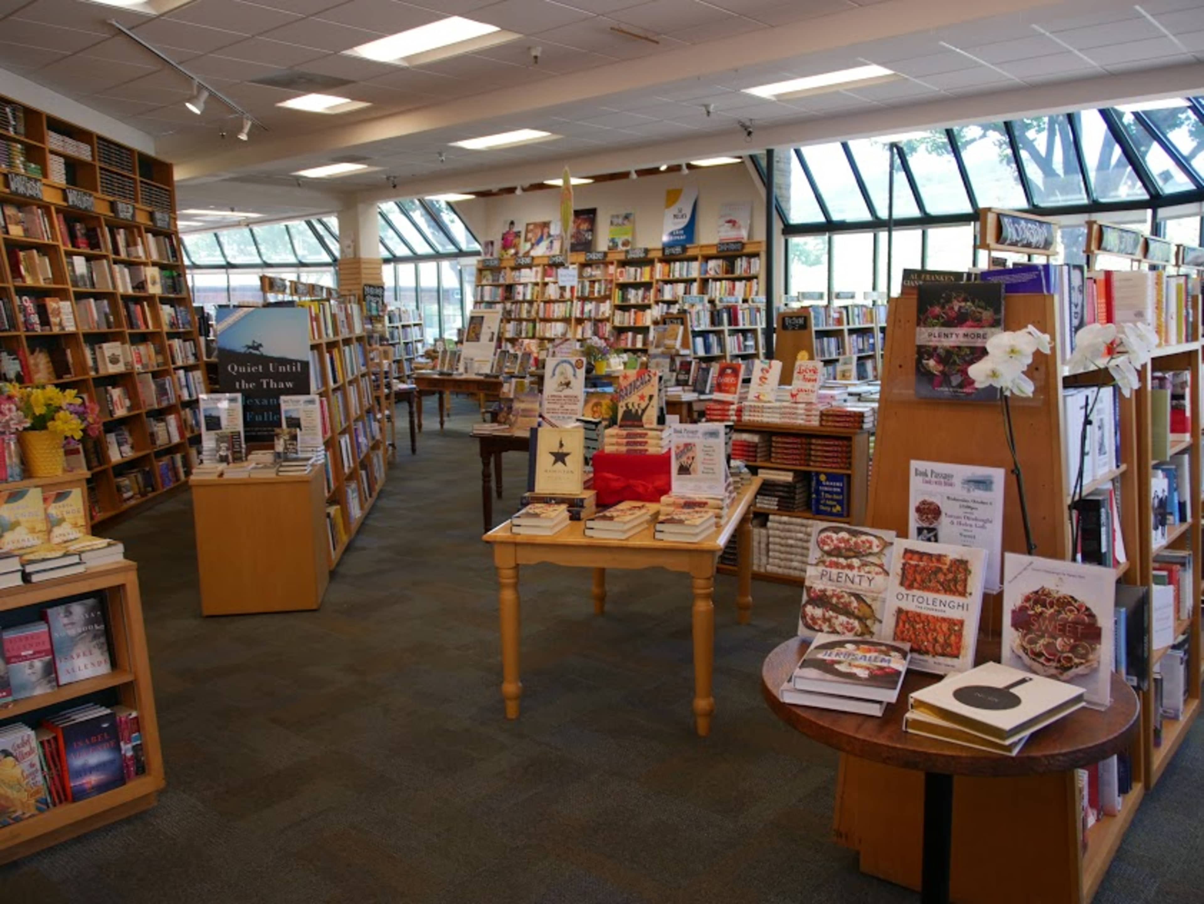 A spacious bookstore filled with neatly organized shelves of books and tables displaying various titles.