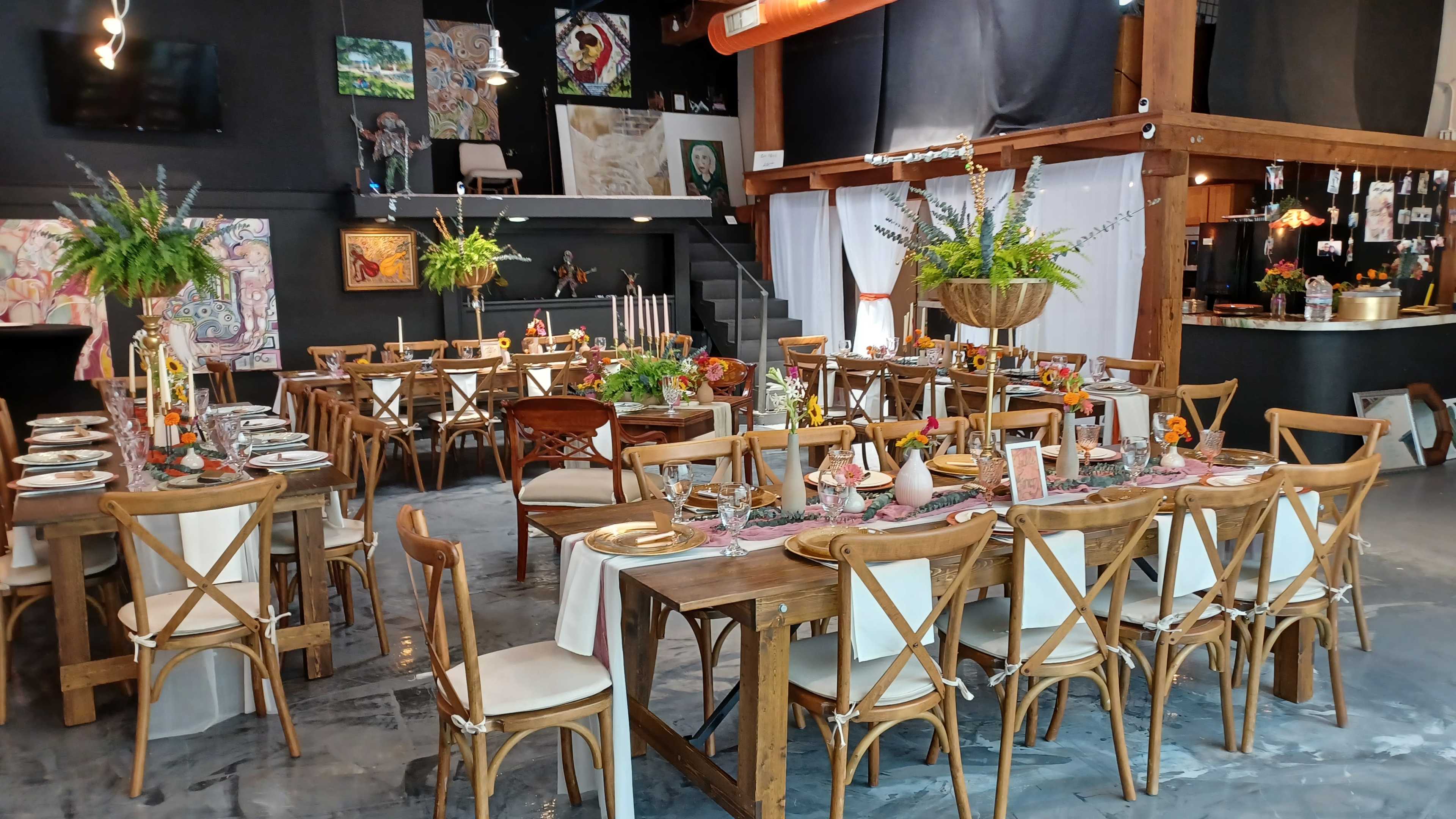 A spacious dining area features wooden tables set with floral centerpieces and candles, surrounded by chairs in a modern restaurant setting.