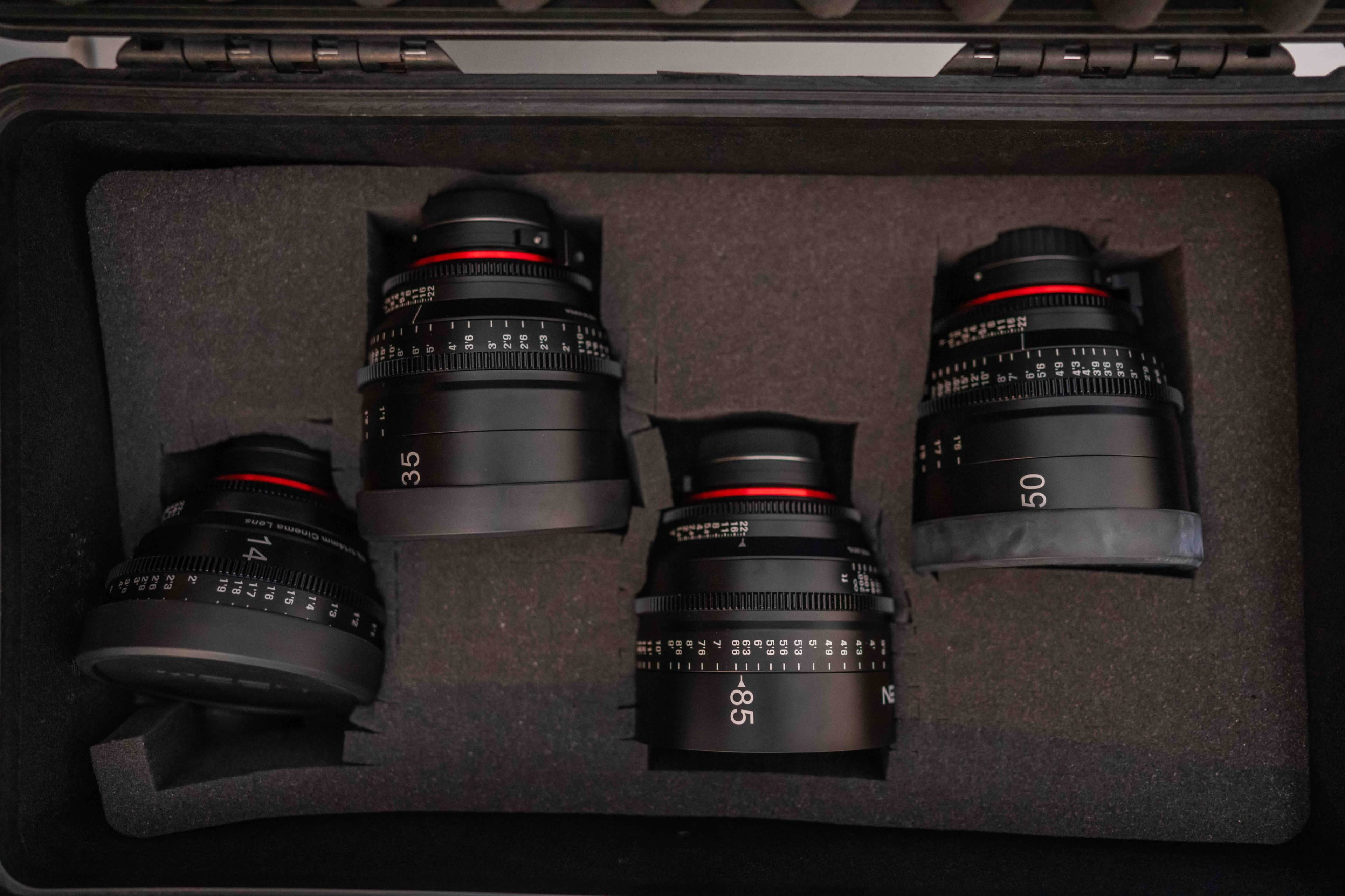 A black case contains four camera lenses, each secured in foam padding.