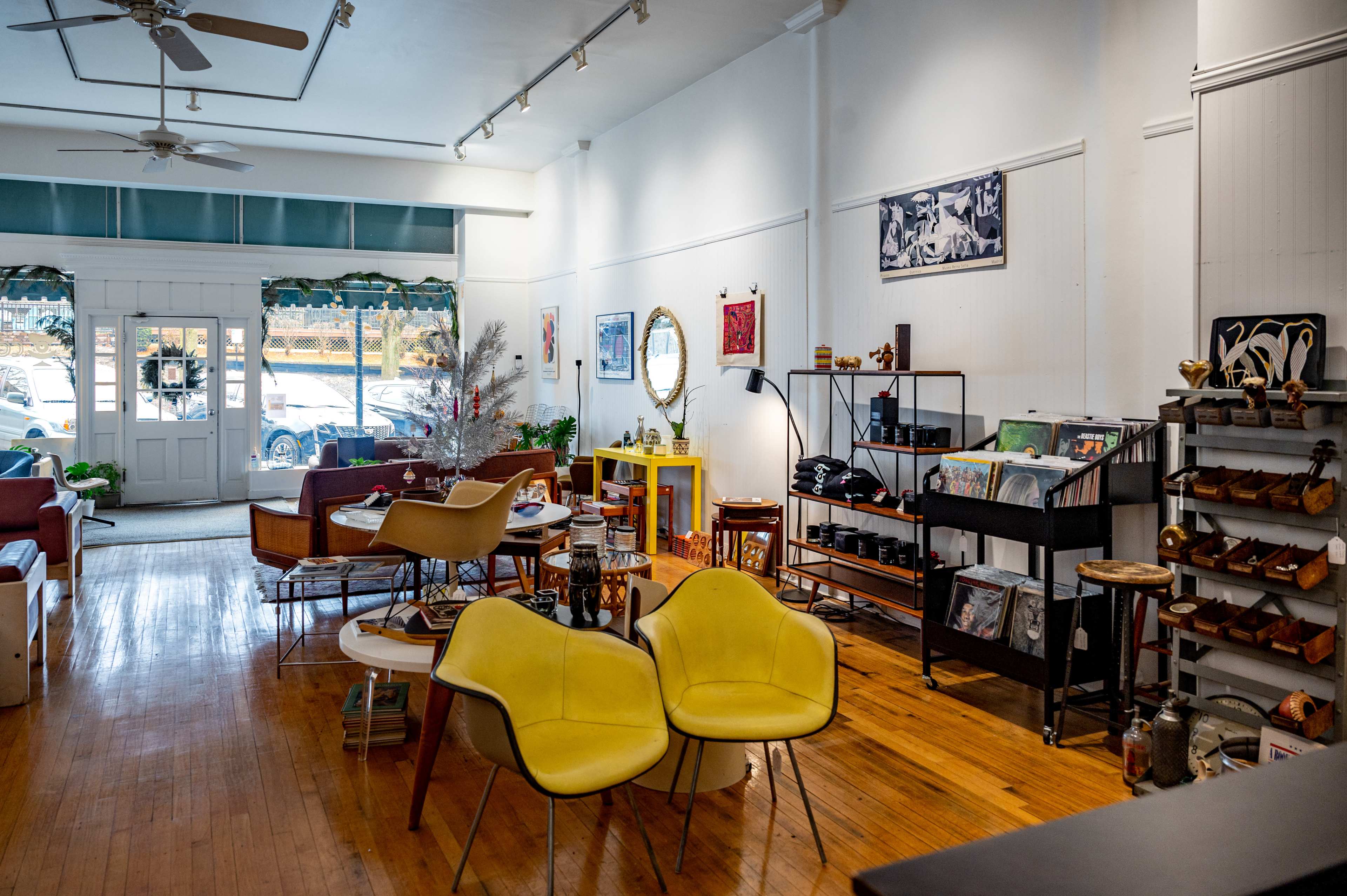 A brightly lit boutique interior featuring modern furniture, decorative items on the walls, and a display shelf with various products.