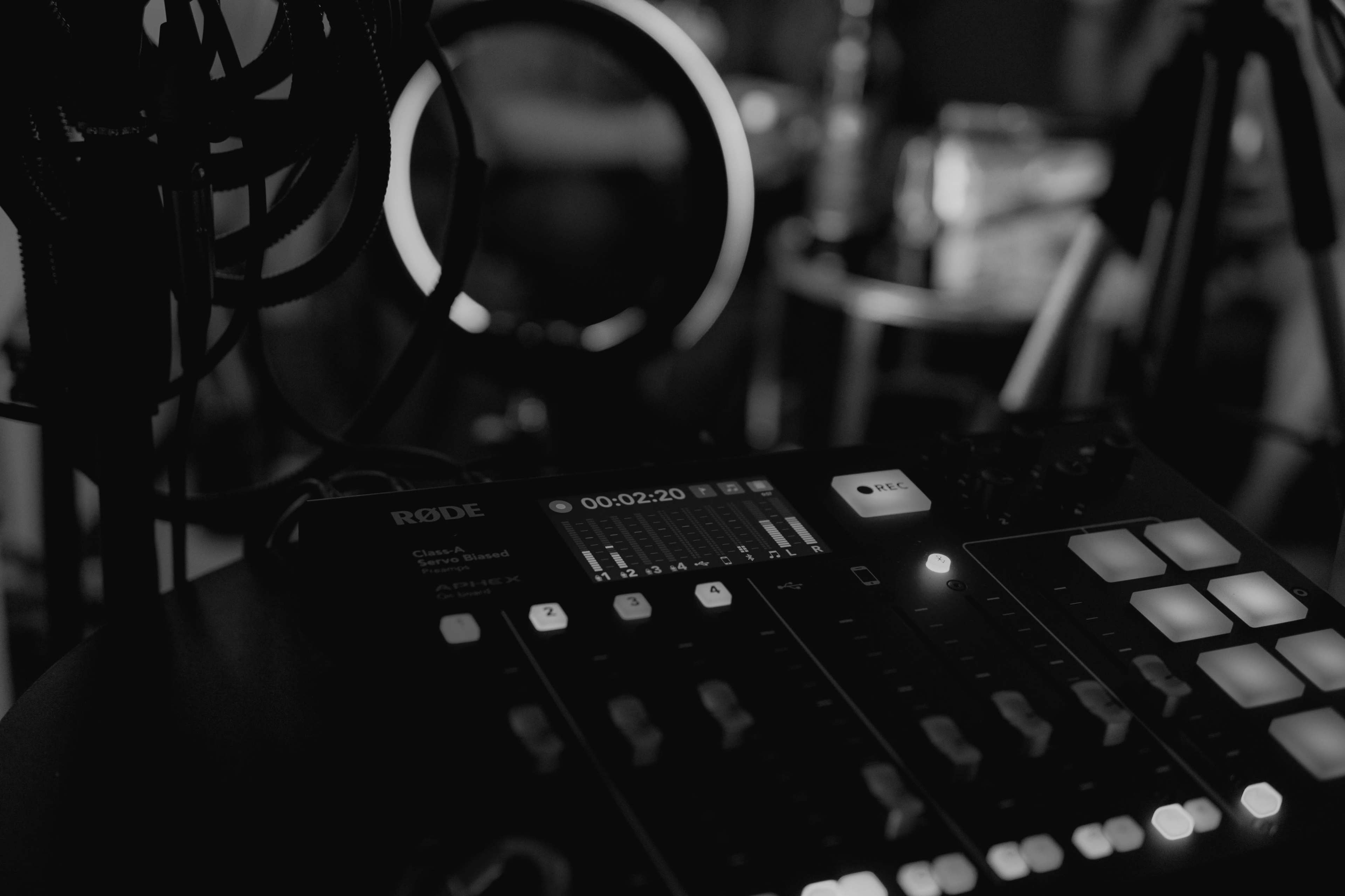 A close-up view of a Rode audio mixer with illuminated buttons and a timer display, set in a dark environment.