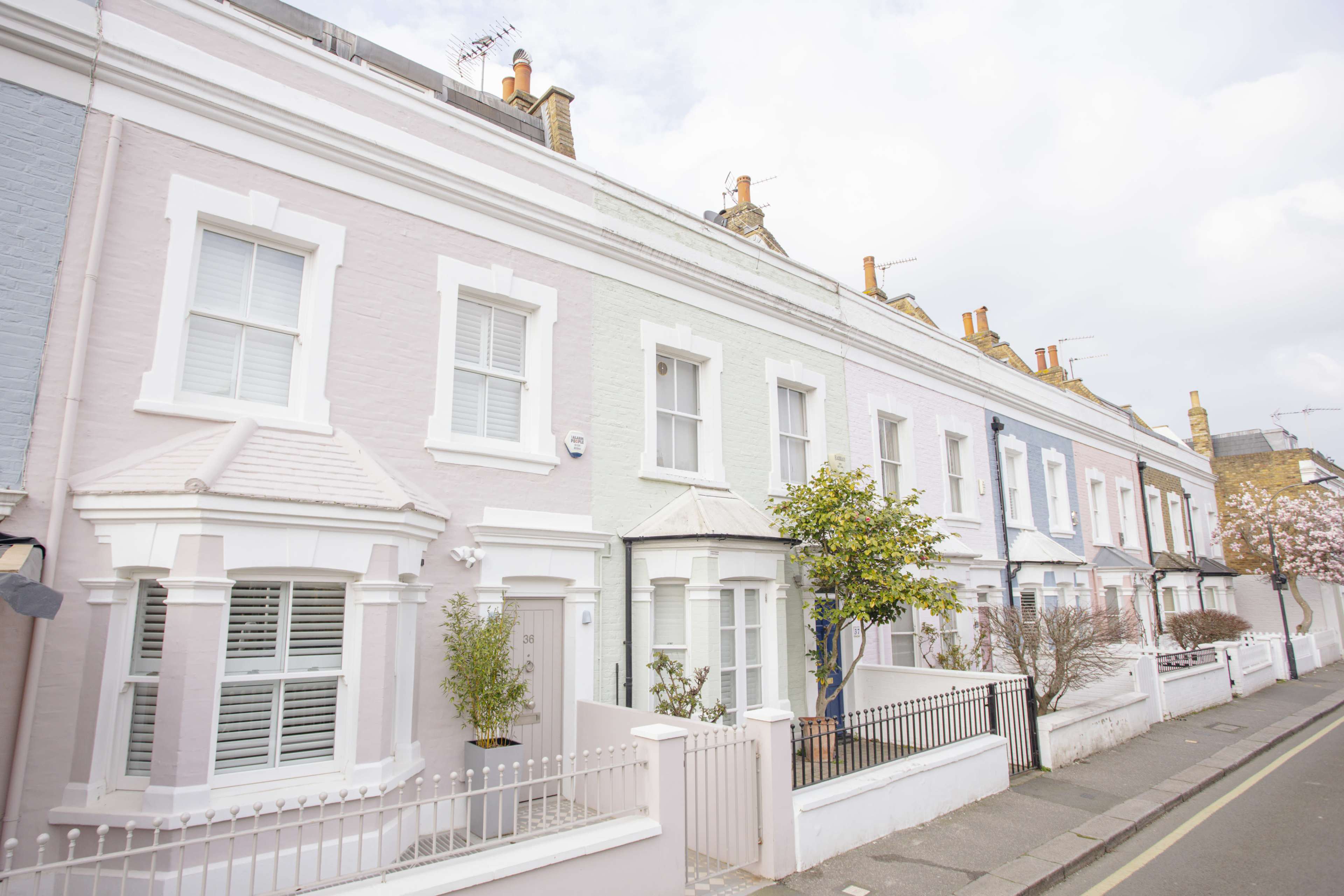 A row of pastel-colored terraced houses with white trim lines a quiet street.
