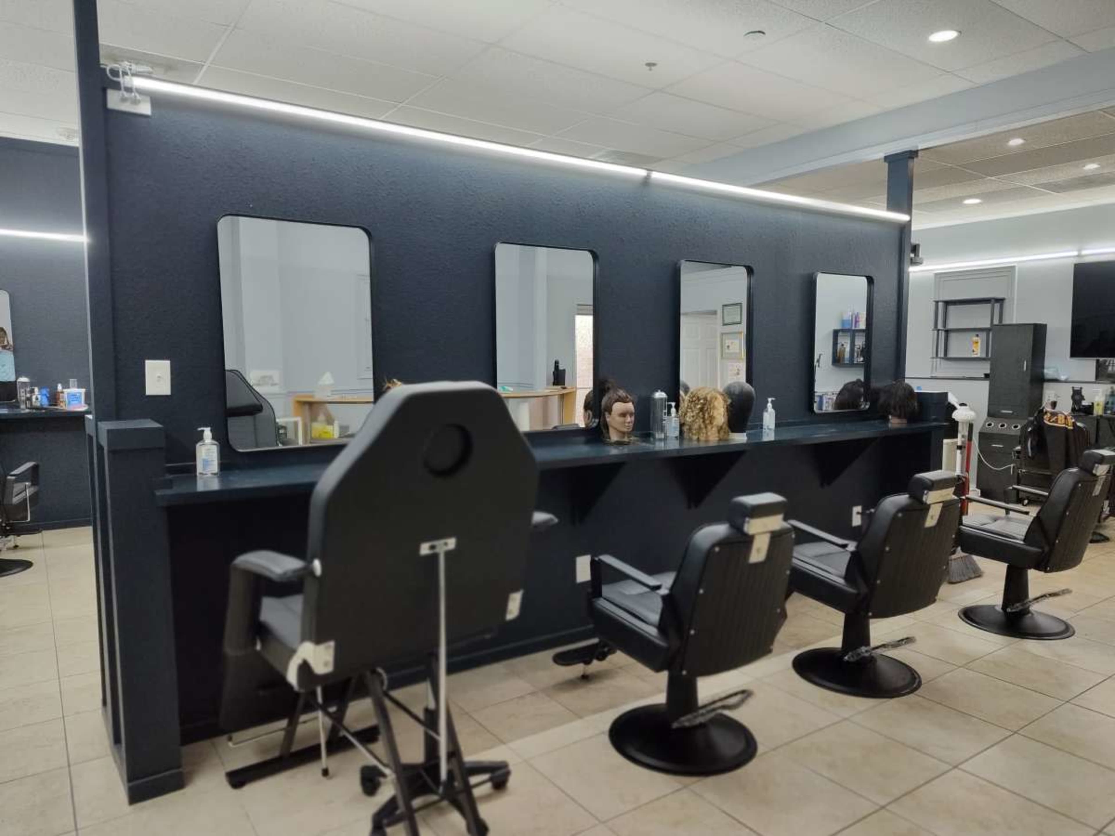 A modern hair salon with empty styling chairs, illuminated mirrors, and a clean, minimalist layout.