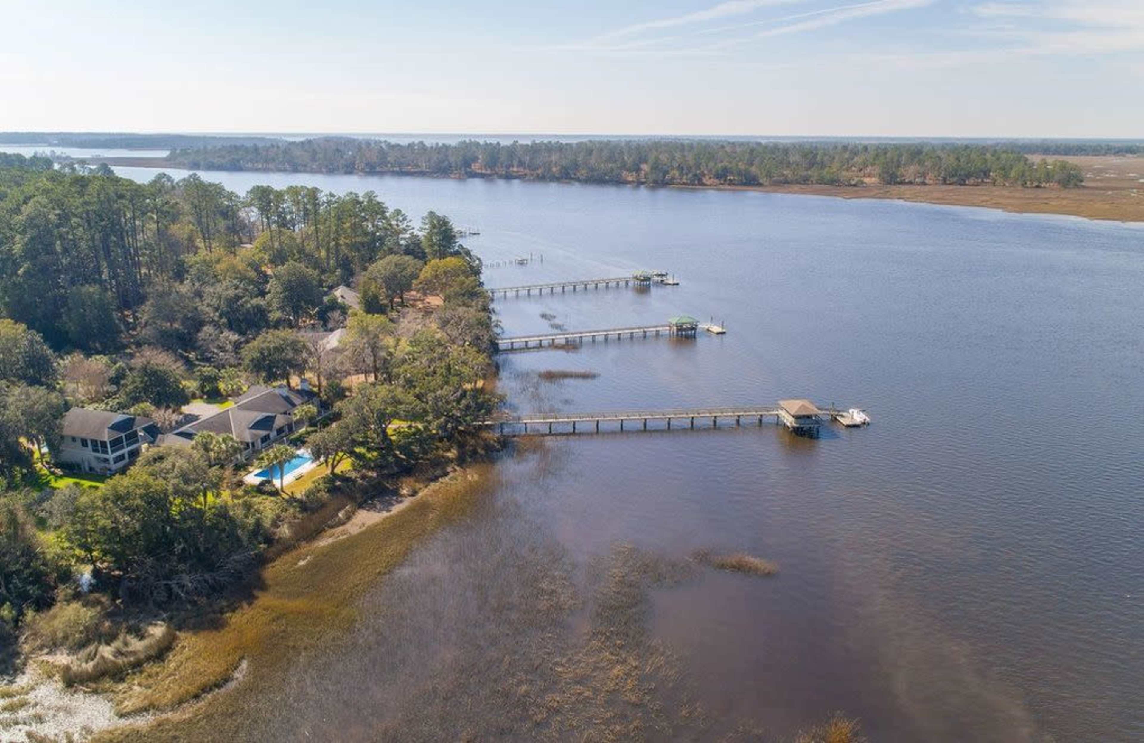 An aerial view of a river landscape featuring docks extending into the water and surrounded by trees.