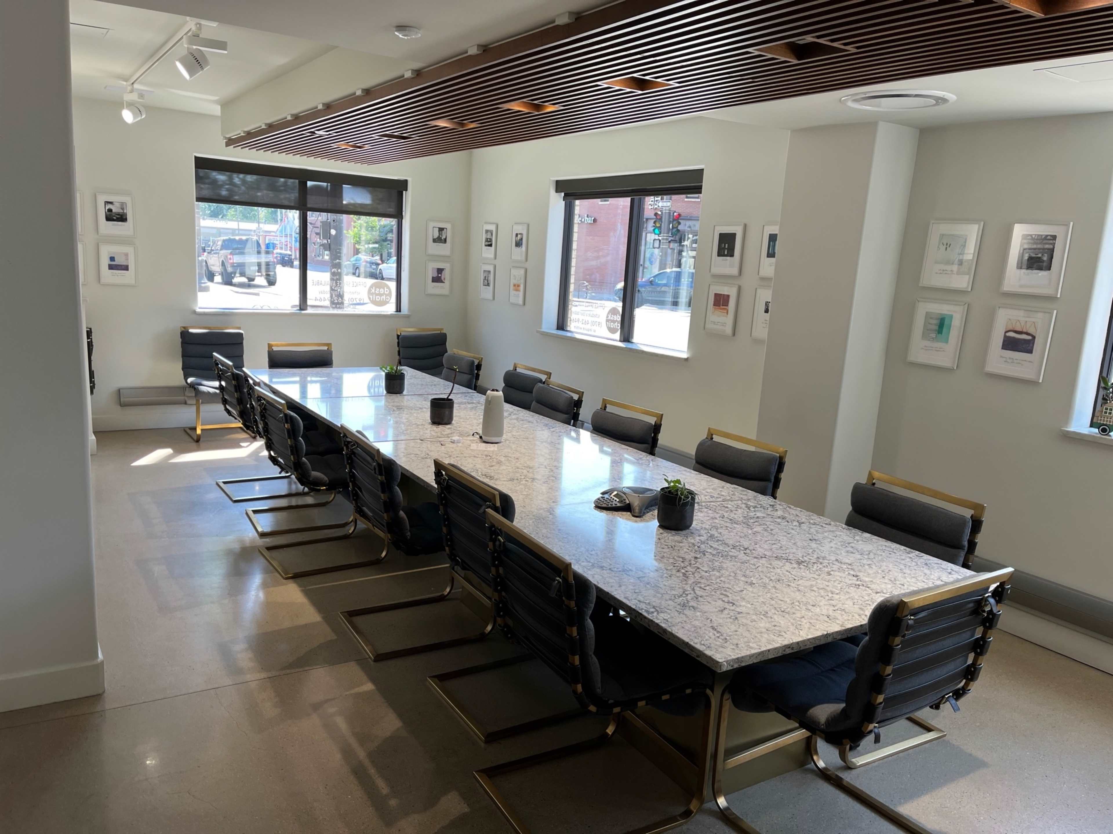 A large, modern conference room with a rectangular granite table surrounded by black chairs and framed artwork on the walls.