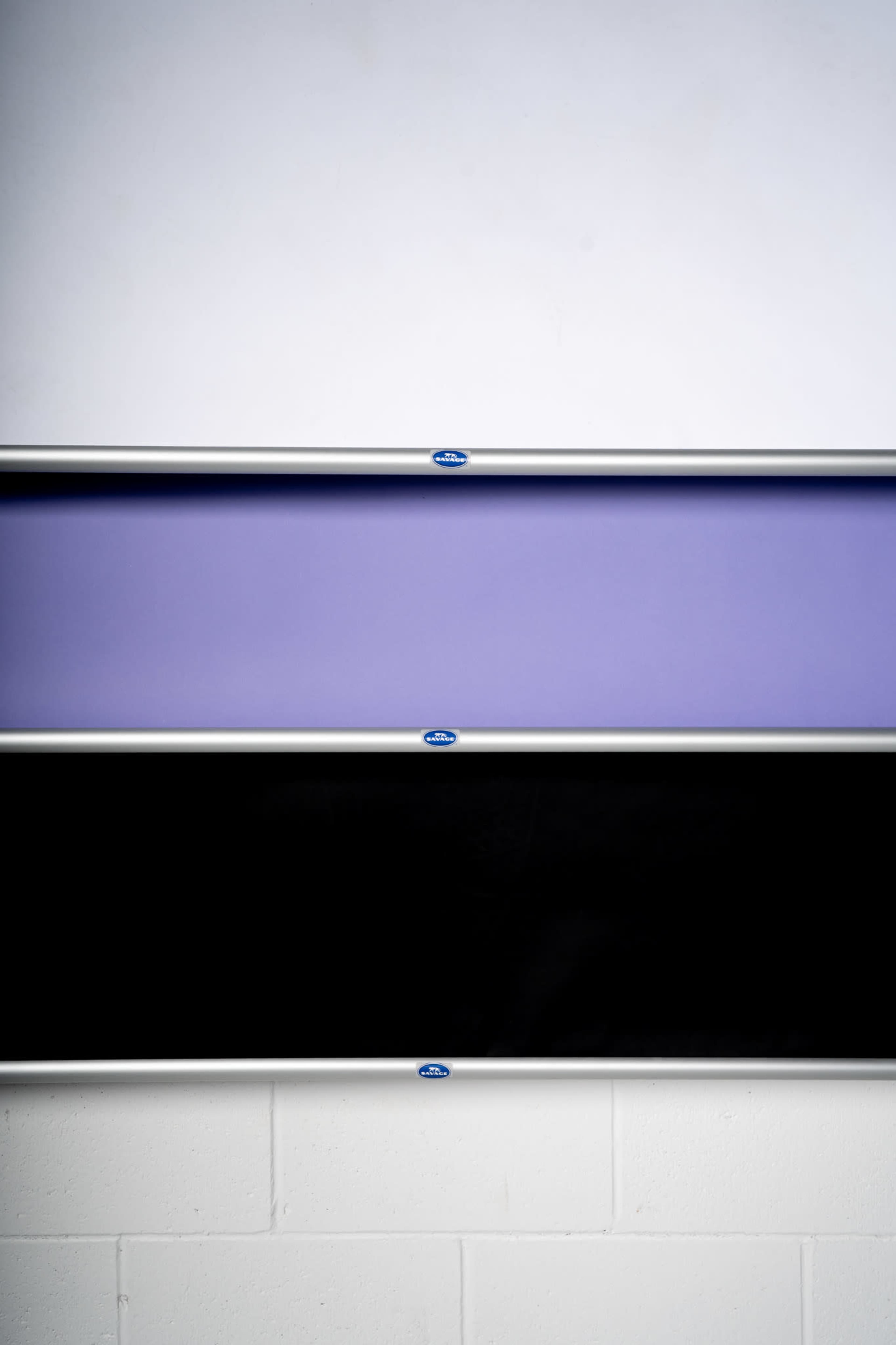 The image features three horizontal panels mounted on a wall, with the top panel white, the middle panel purple, and the bottom panel black.