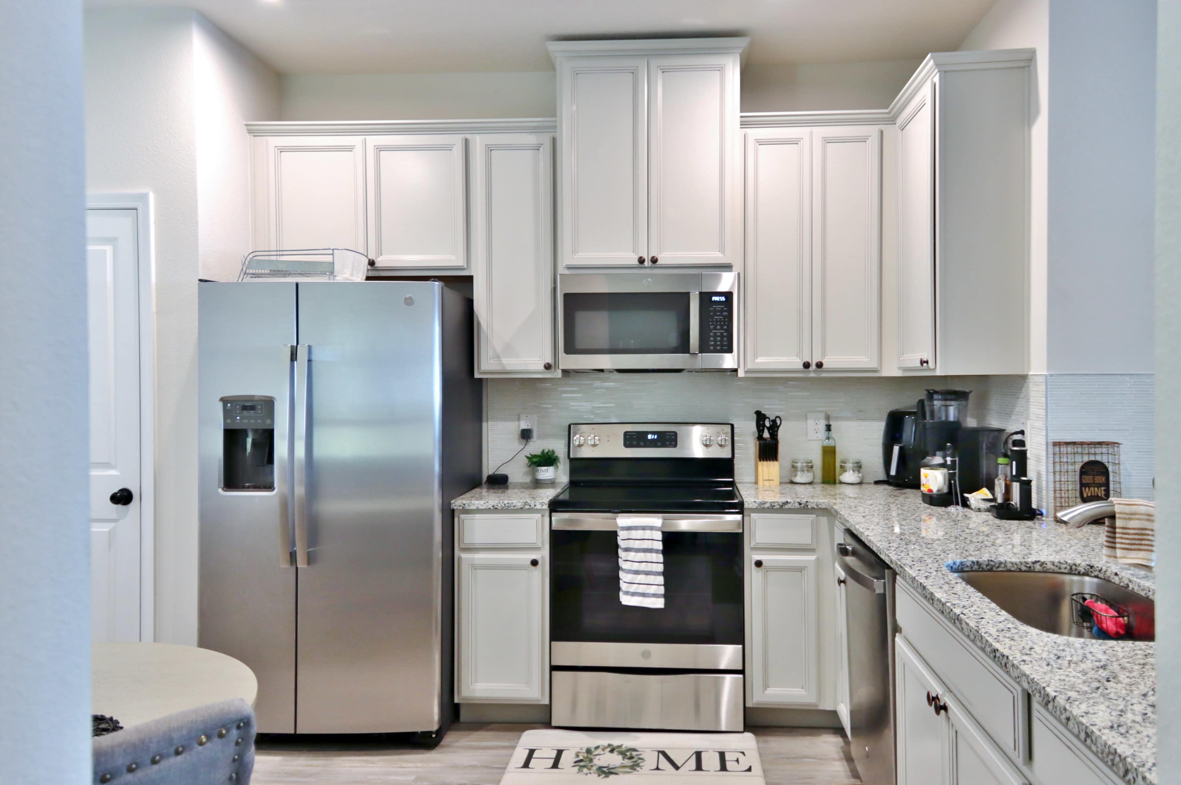 The kitchen features white cabinetry, stainless steel appliances, and a gray granite countertop.