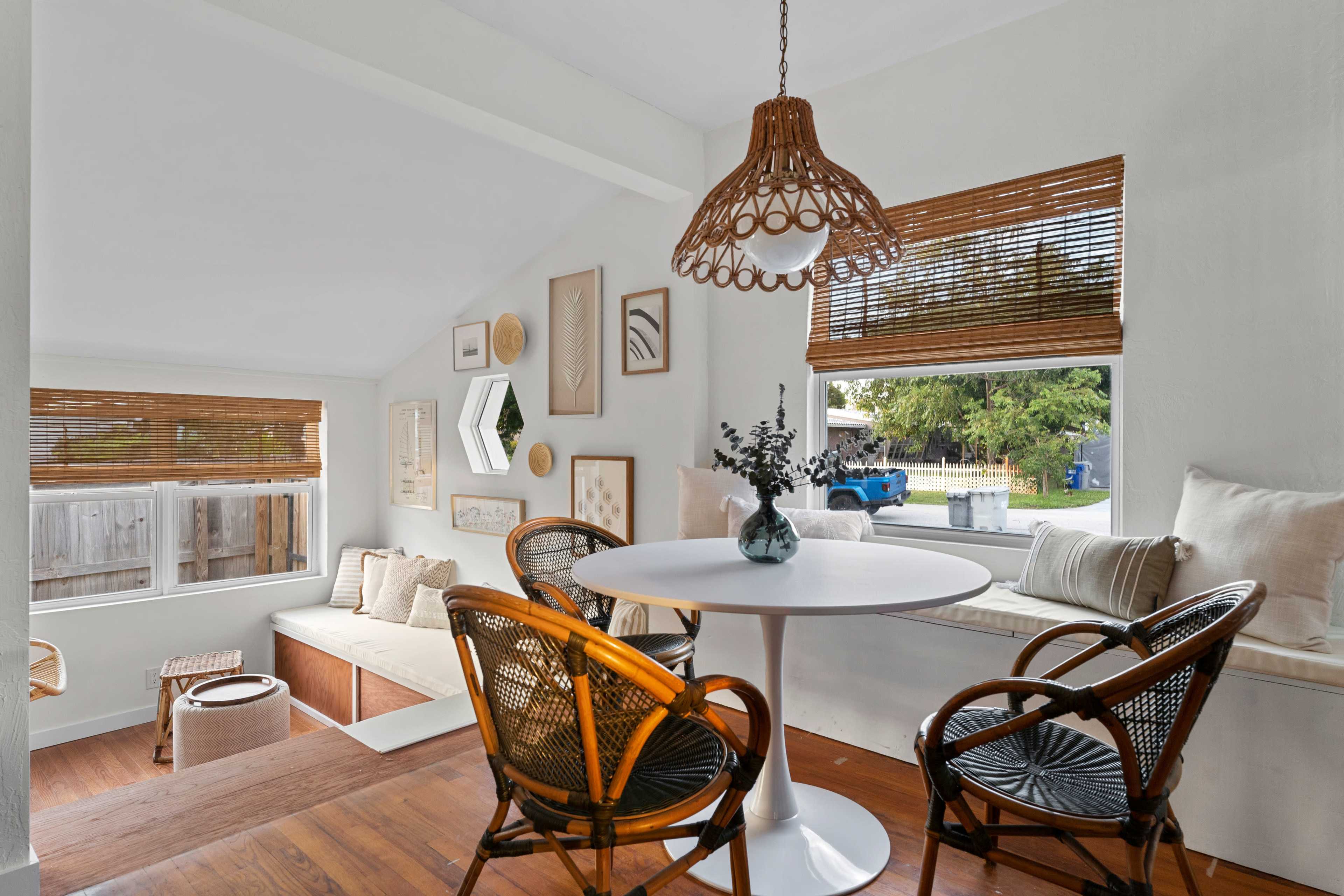 A cozy dining area features a round table with woven chairs, surrounded by warm wood accents and decorated walls.