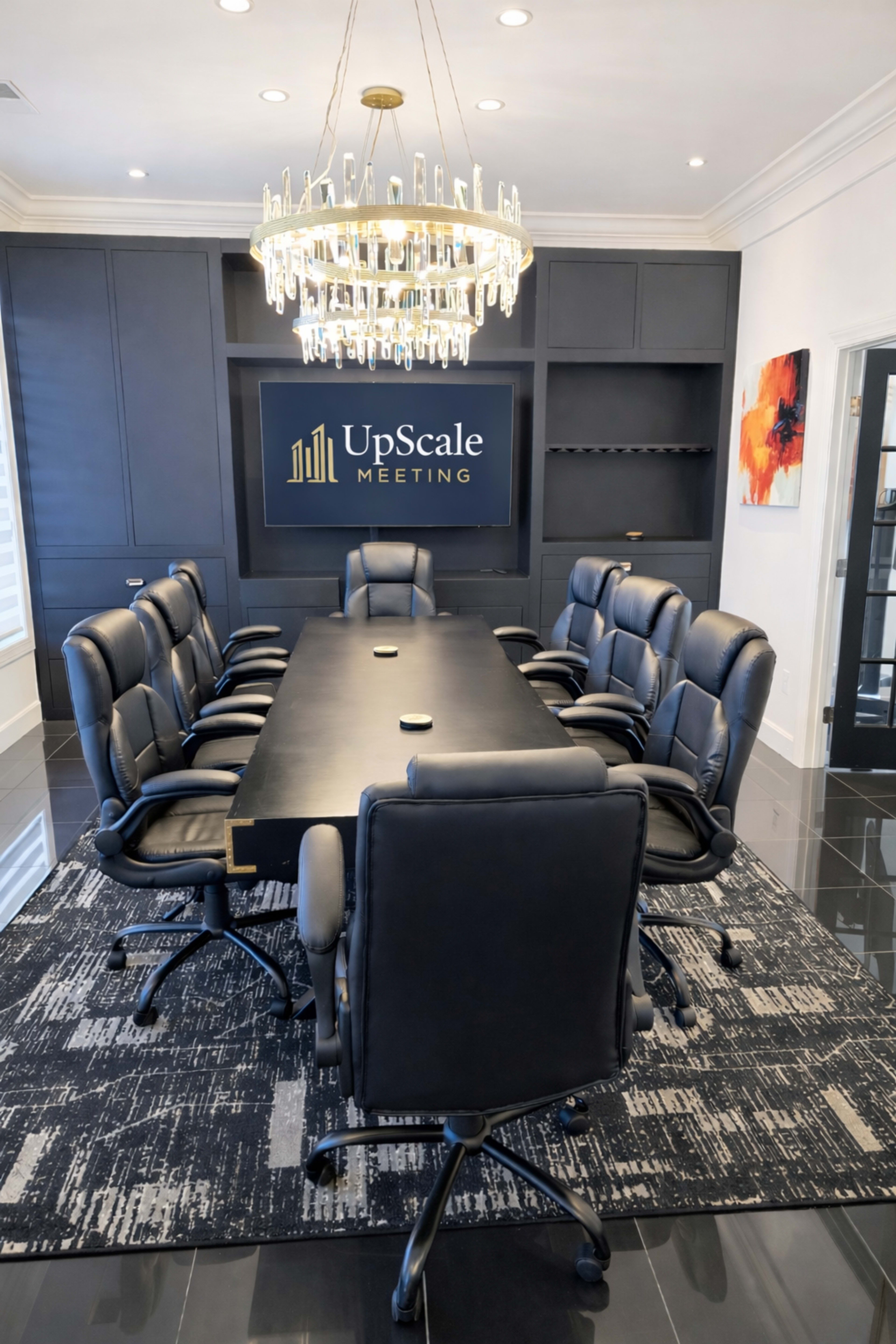 The image shows a modern conference room with a long black table, black leather chairs, a chandelier, and a wall featuring the text "UpScale Meeting."