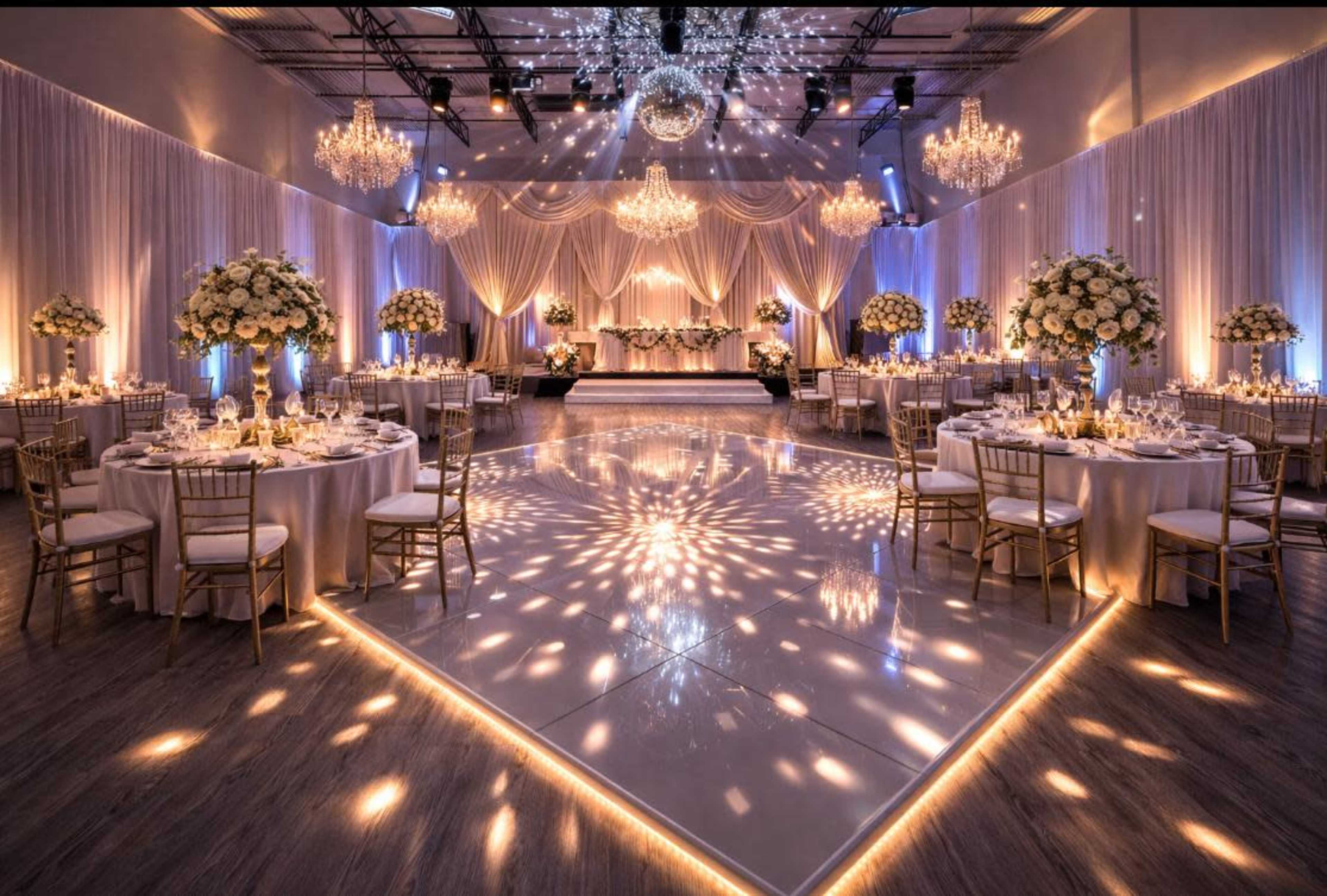 The image shows a beautifully decorated event space with round tables, elegant centerpieces, and dramatic lighting, featuring a dance floor illuminated by patterned lights.