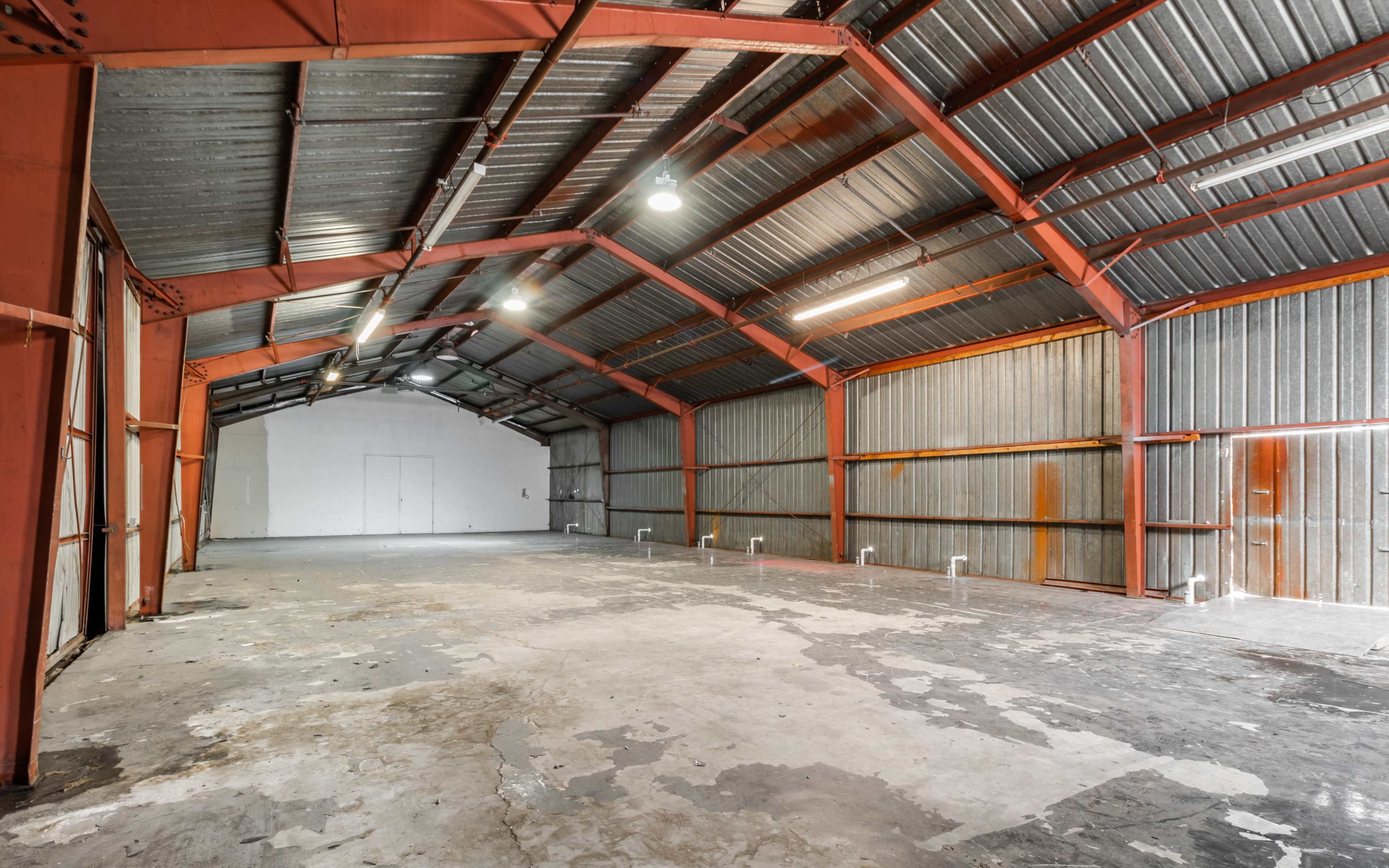 A spacious, empty industrial warehouse with metal walls and a high ceiling.