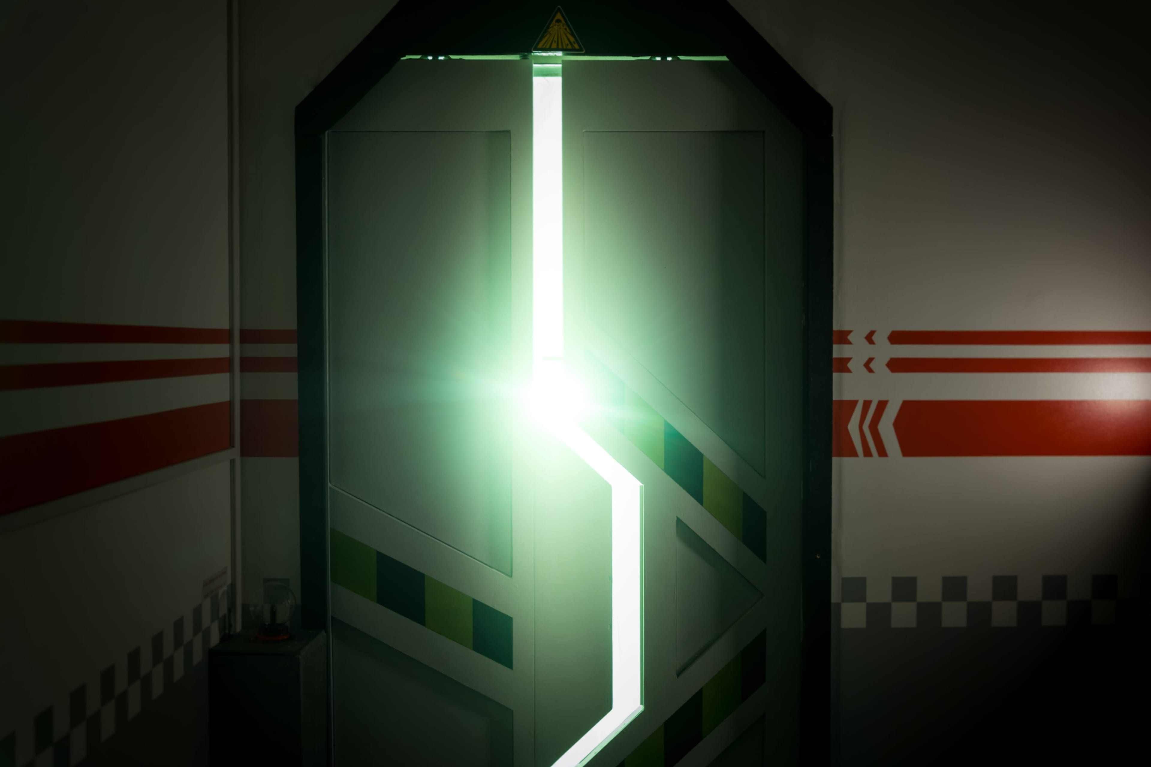 A doorway is partially open, revealing a bright light shining through the gap, with striped marks on the surrounding wall.