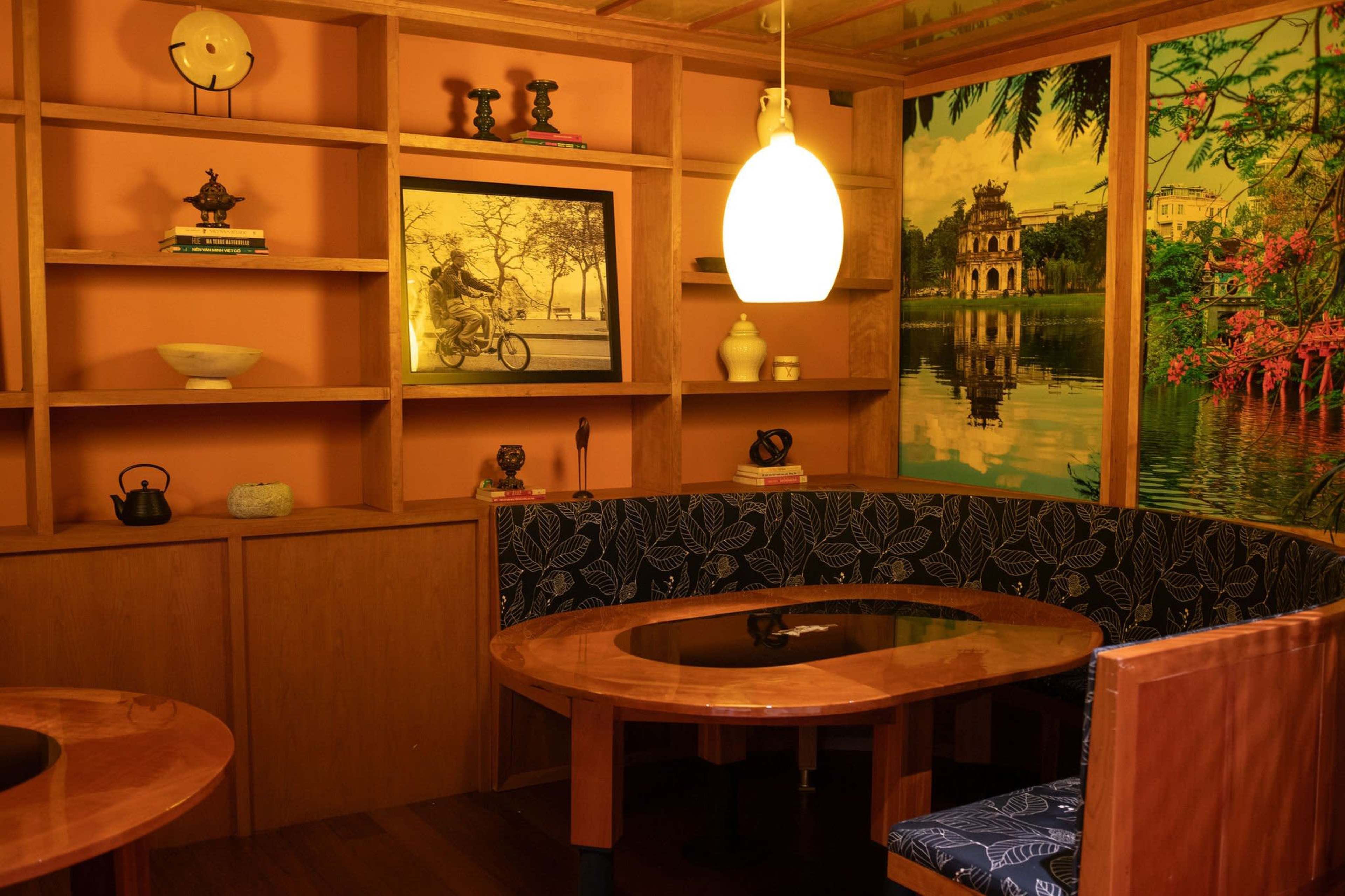 A cozy interior features wooden shelving with decorative items, an oval table, and a unique light fixture.