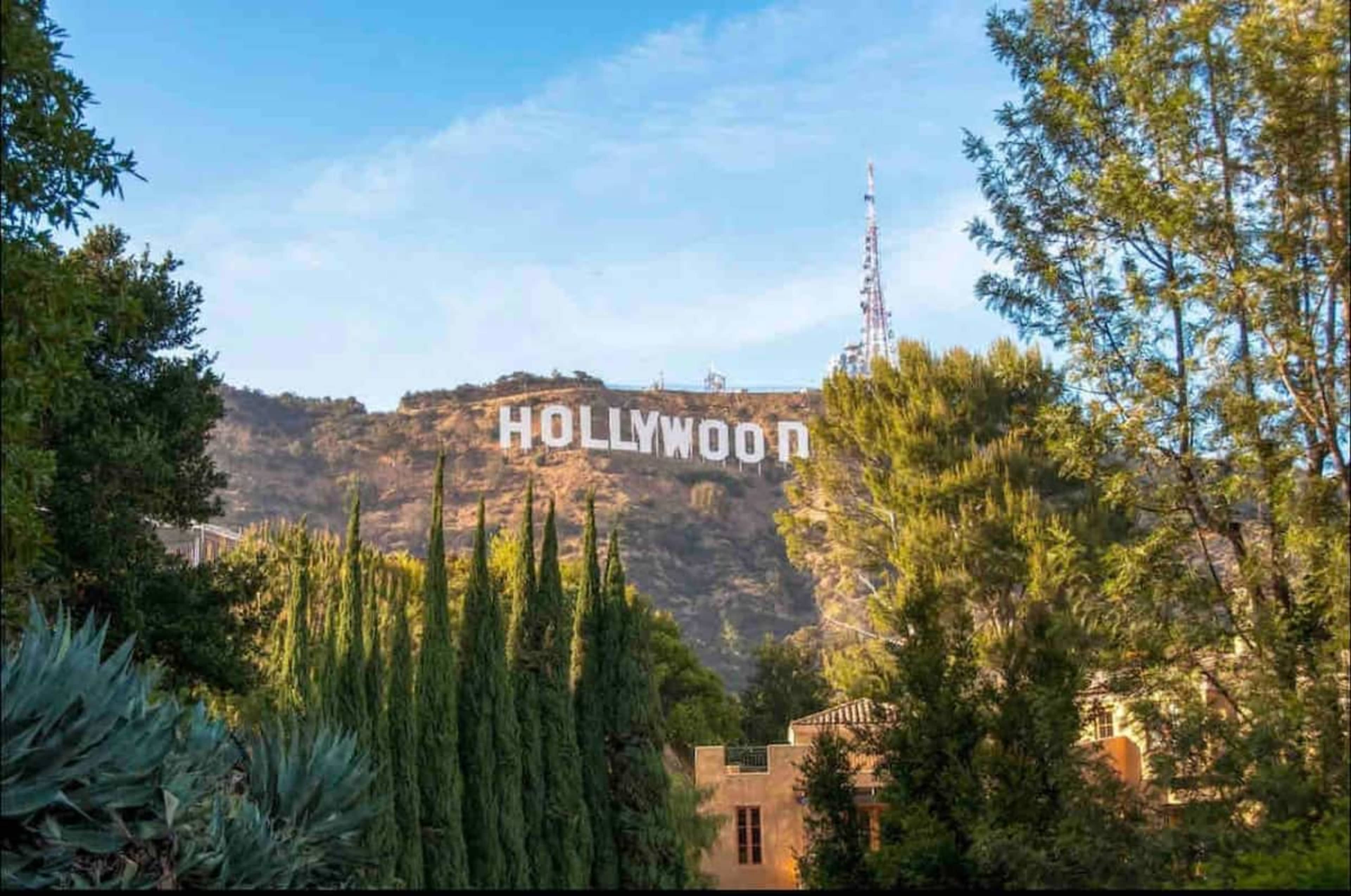 The Hollywood sign is prominently displayed on a hillside, surrounded by trees and vegetation.