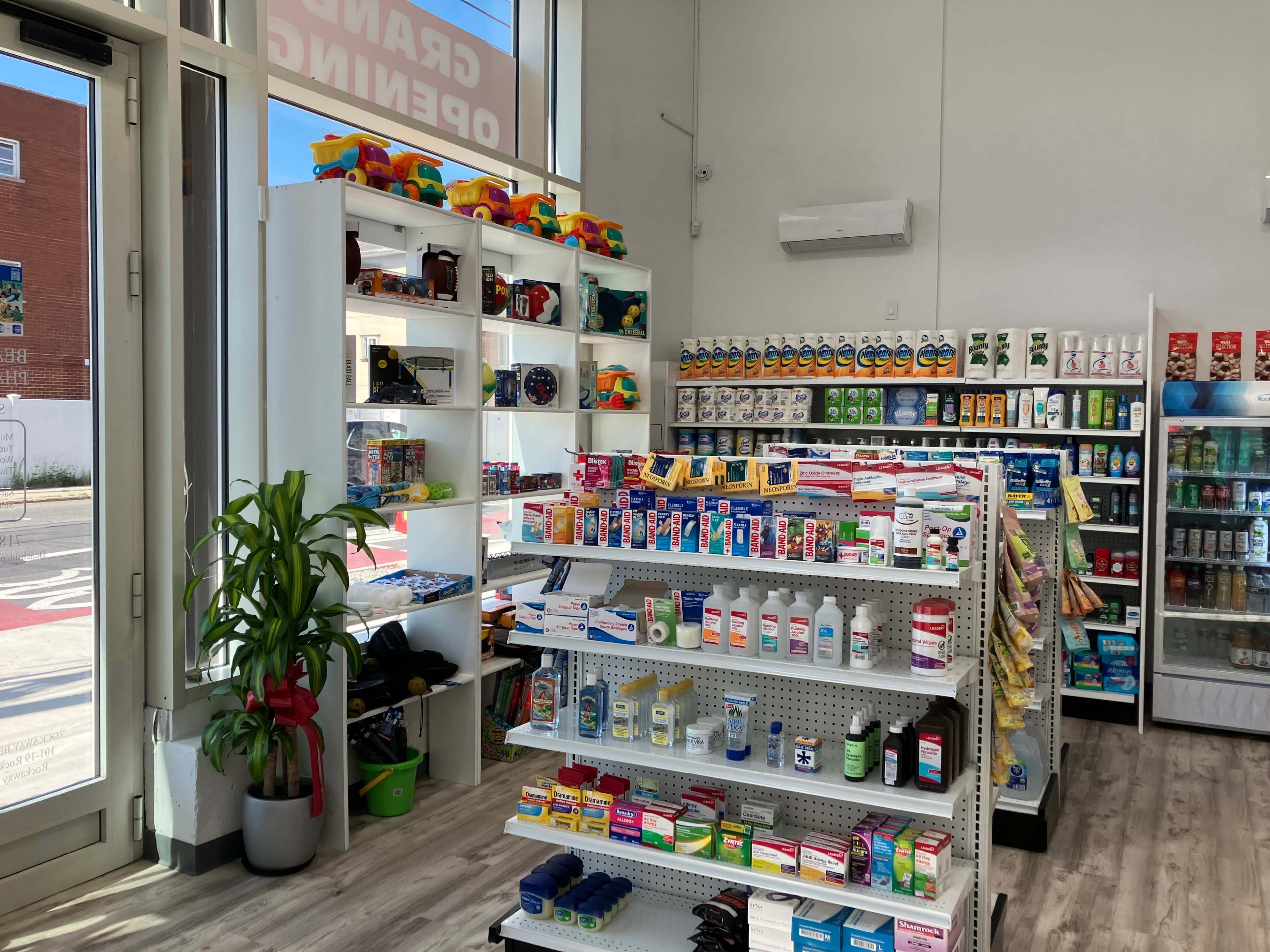 The interior of a store features shelves stocked with various health and beauty products, along with toys and household items, illuminated by natural light from large windows.