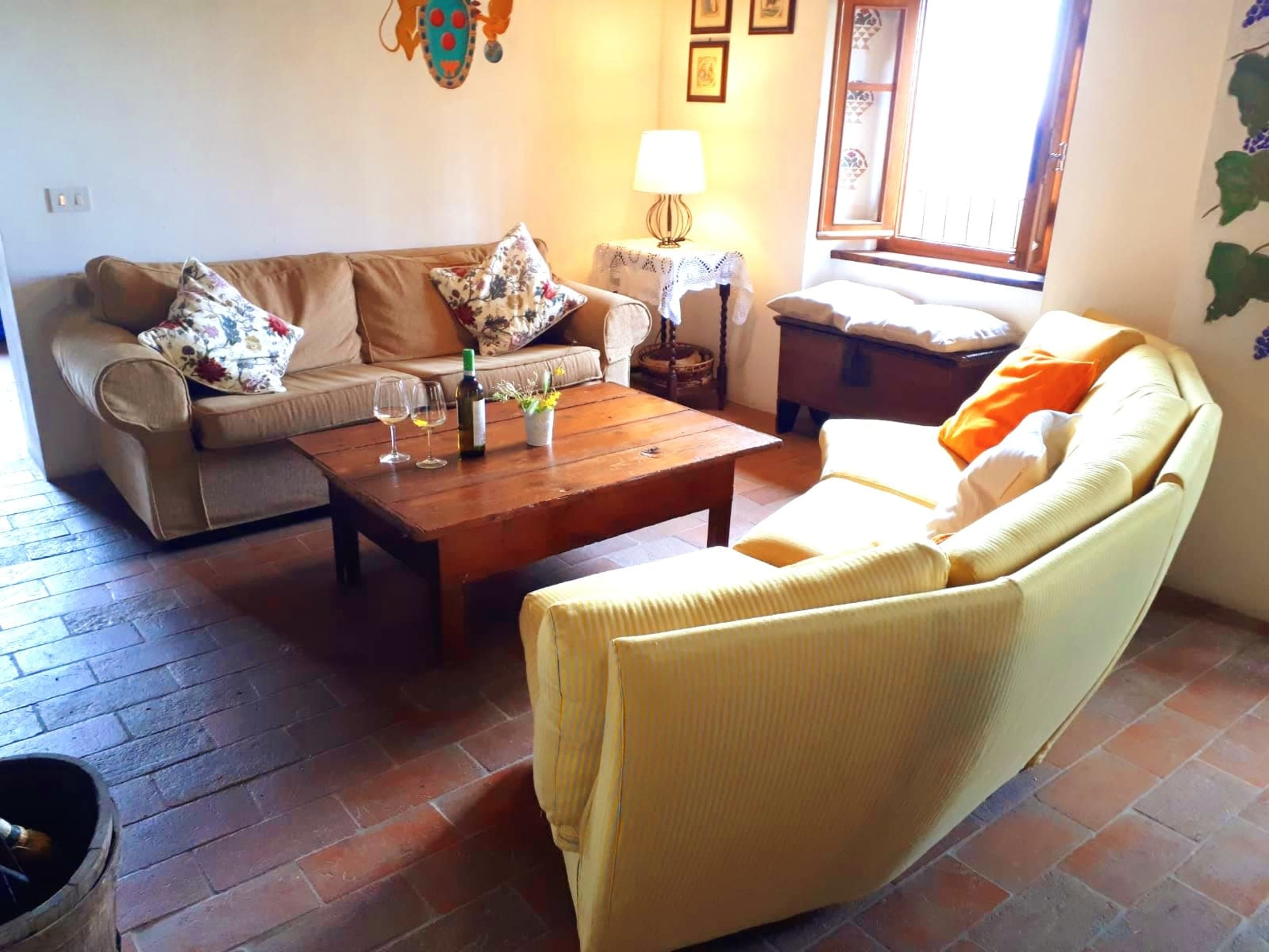 The image shows a living room with two sofas, a wooden coffee table, and a window with natural light.