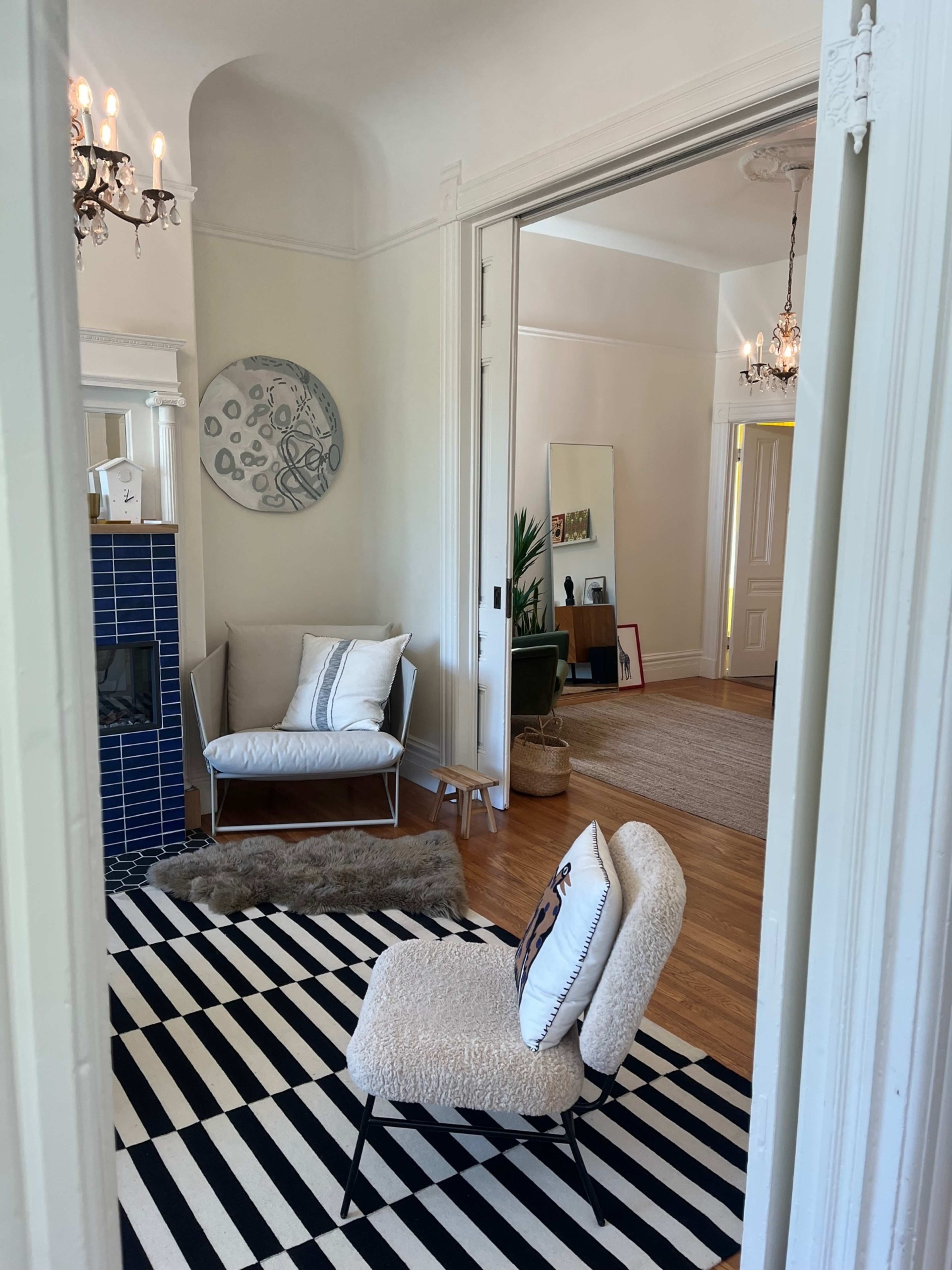 A doorway frames a stylish living room featuring a blue tiled fireplace, a patterned rug, and contemporary furniture.