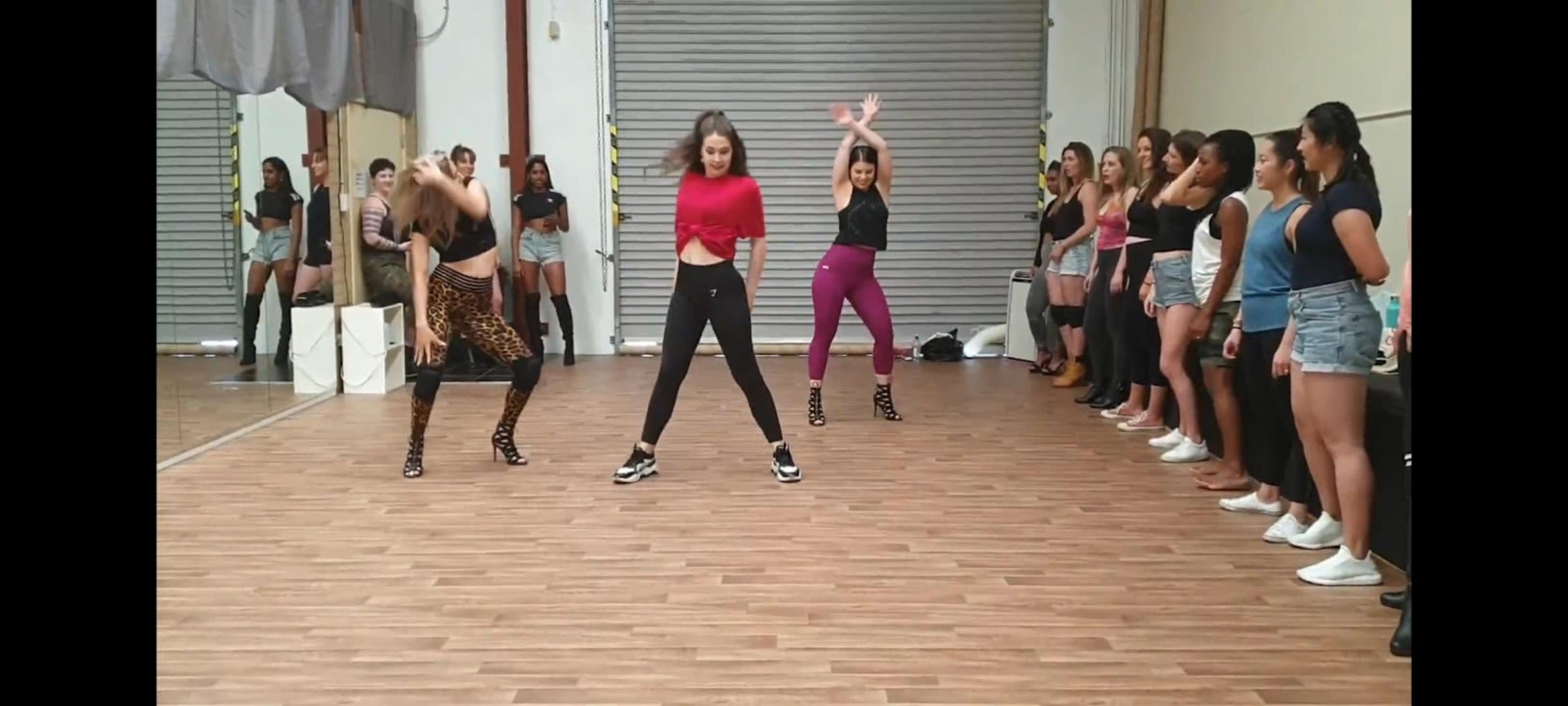 Three dancers perform in front of an audience, while several spectators watch from the sidelines.
