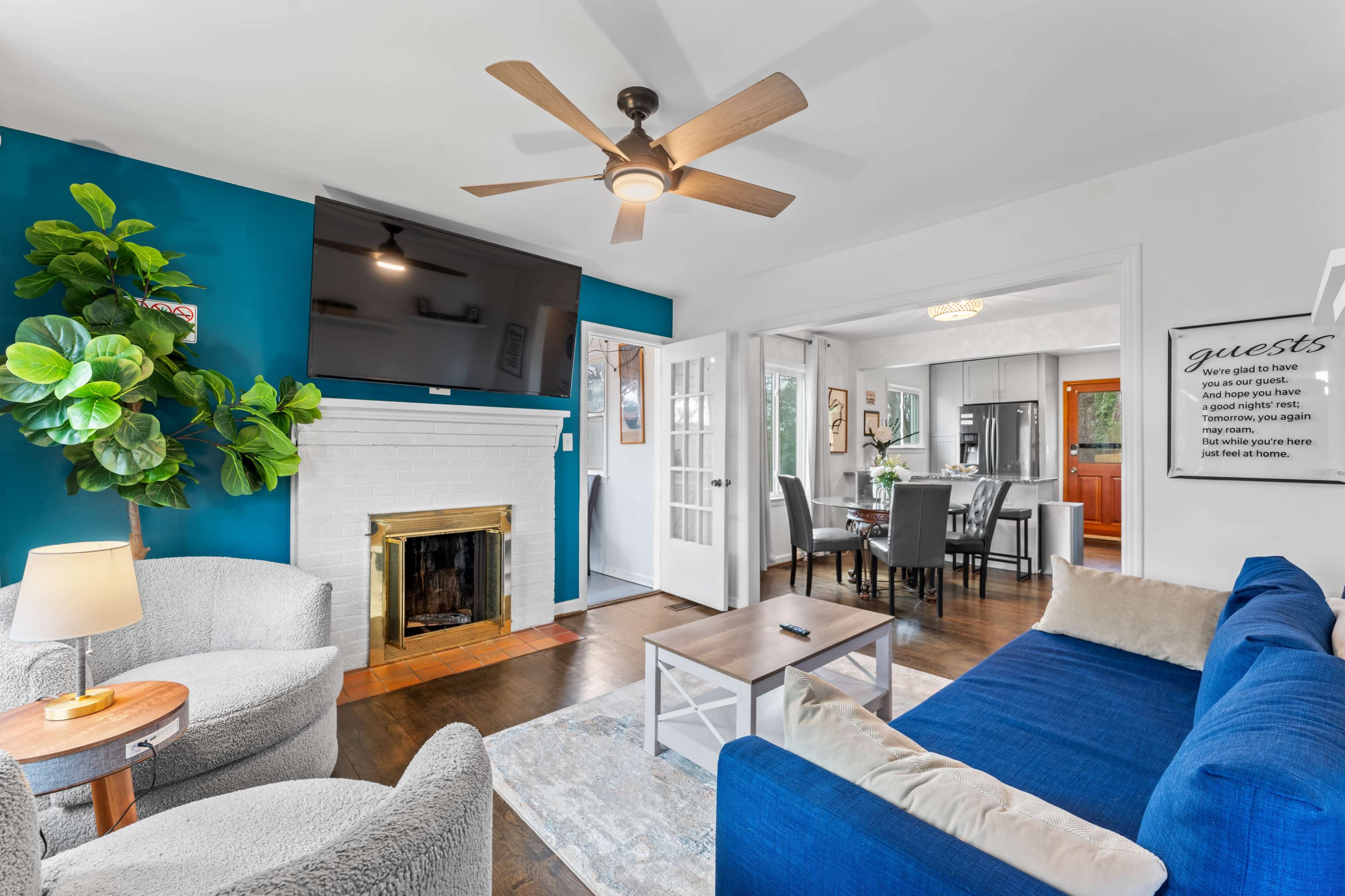 The image shows a cozy living room with a blue accent wall, a fireplace, and furniture arranged for relaxation and socializing.