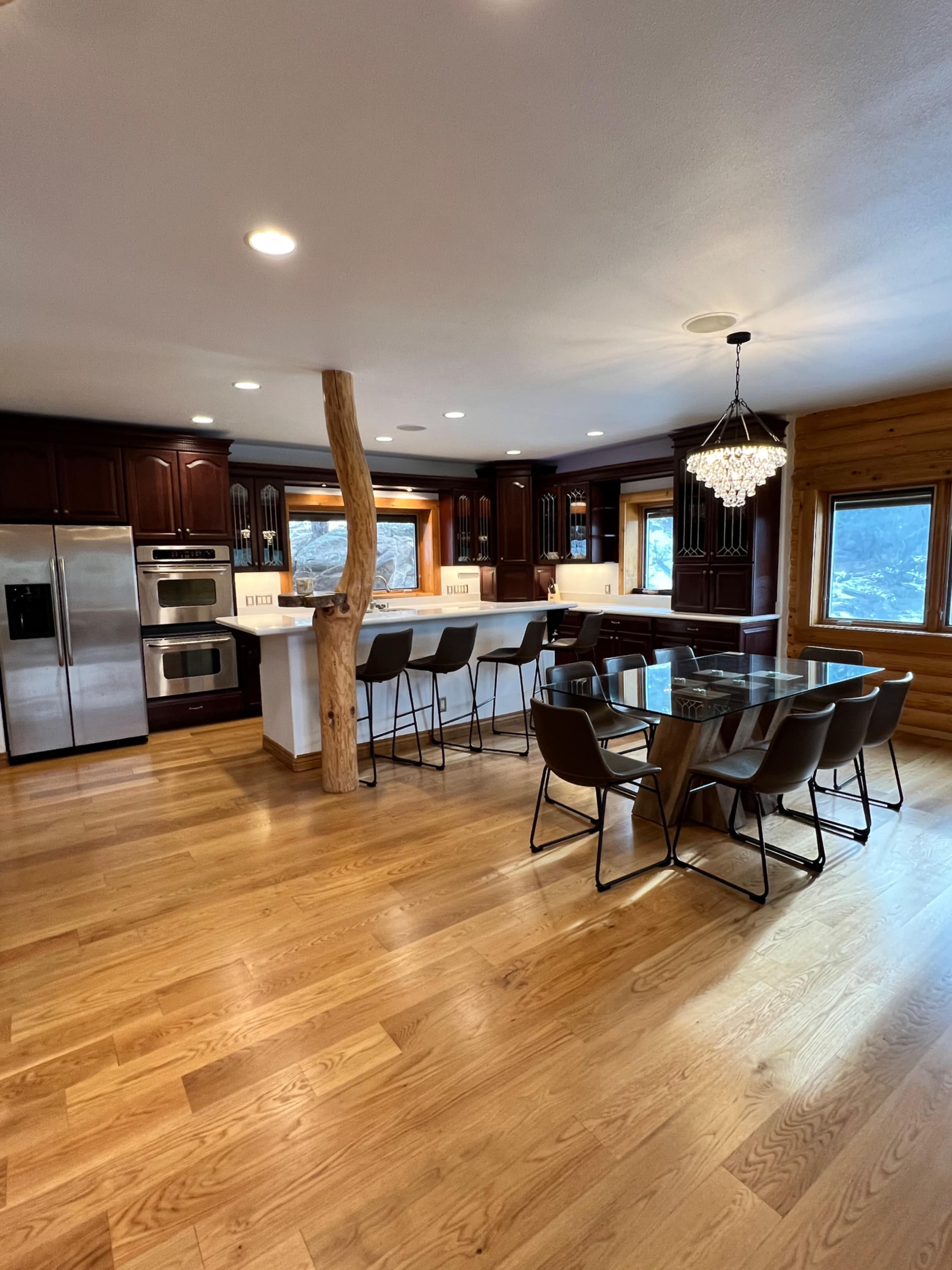 The kitchen features dark wooden cabinetry, stainless steel appliances, and a large island with seating, illuminated by a chandelier.