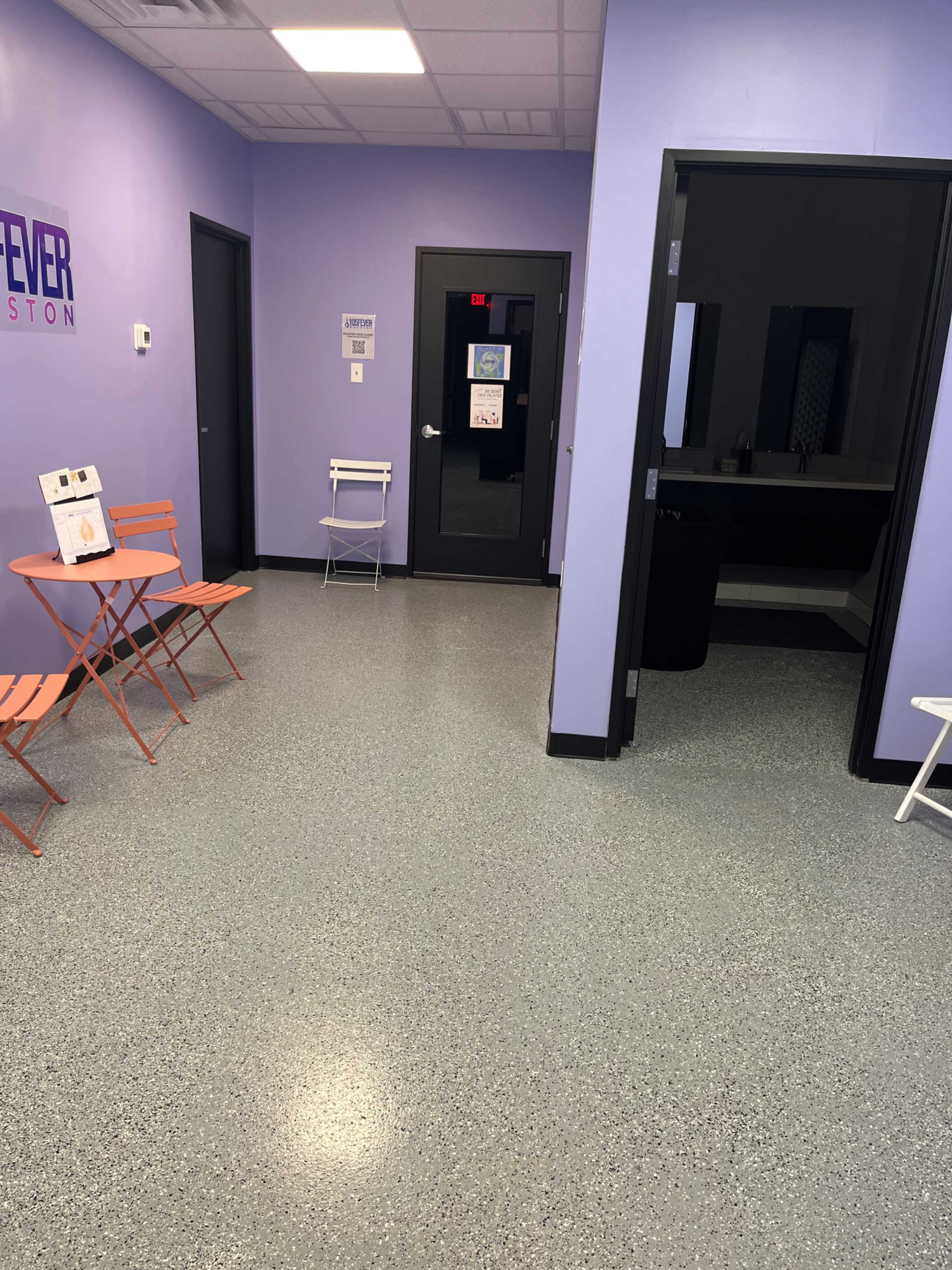 A reception area with purple walls, a small table and chairs, and a doorway leading to another room.