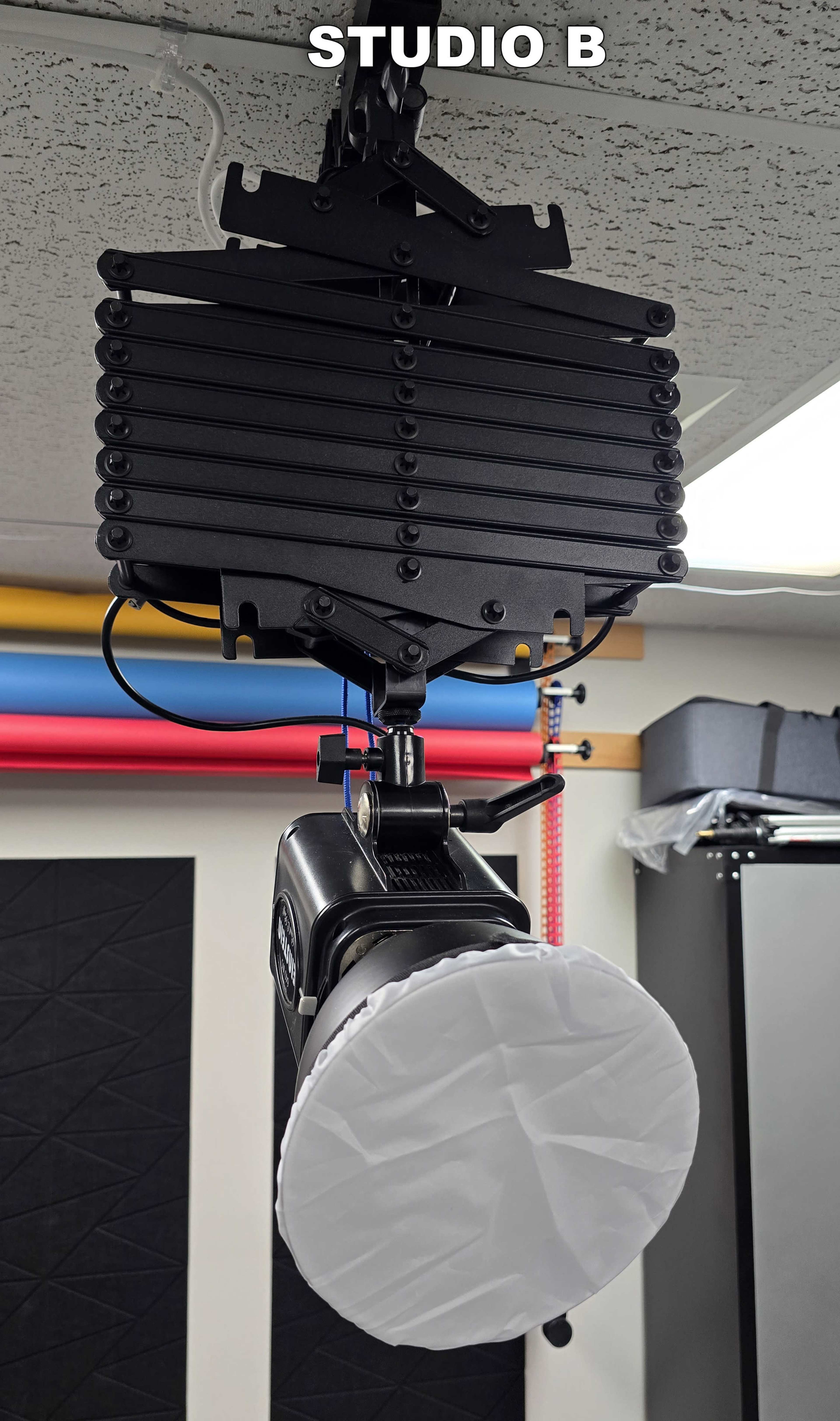A studio lighting setup with a softbox hanging from a black mounting system in a photography studio.