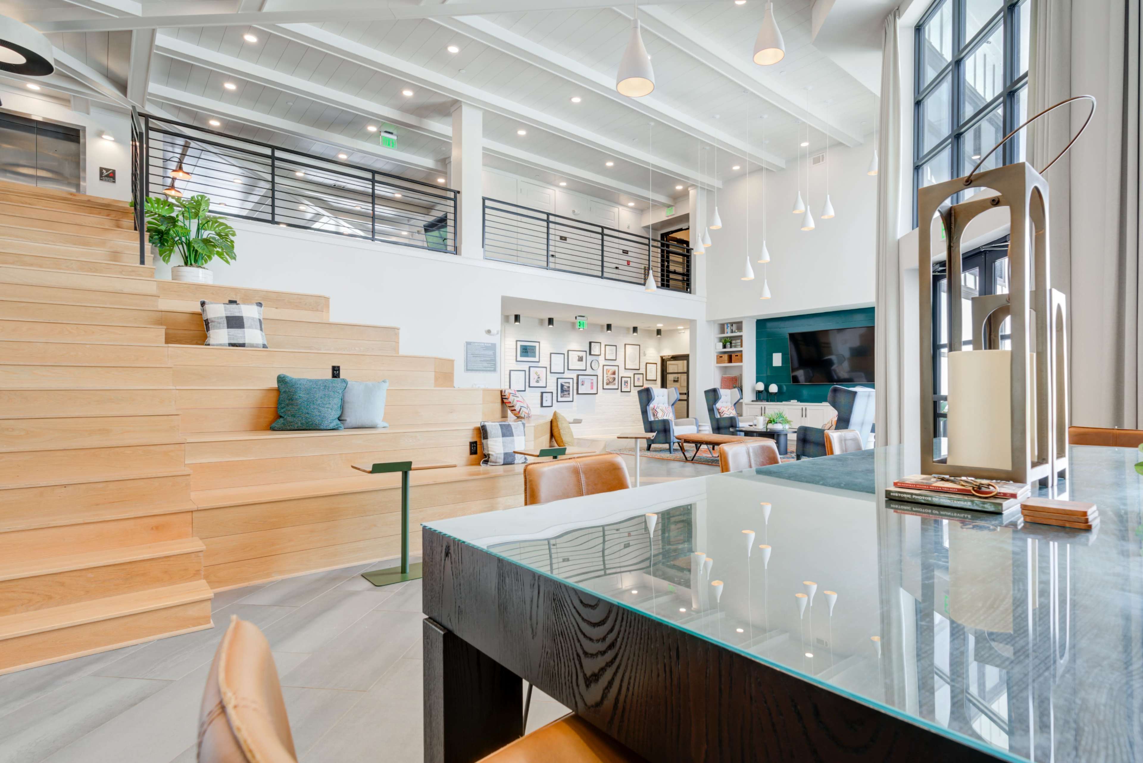A modern interior space featuring wooden stairs, a glass table, and a wall adorned with framed photographs.