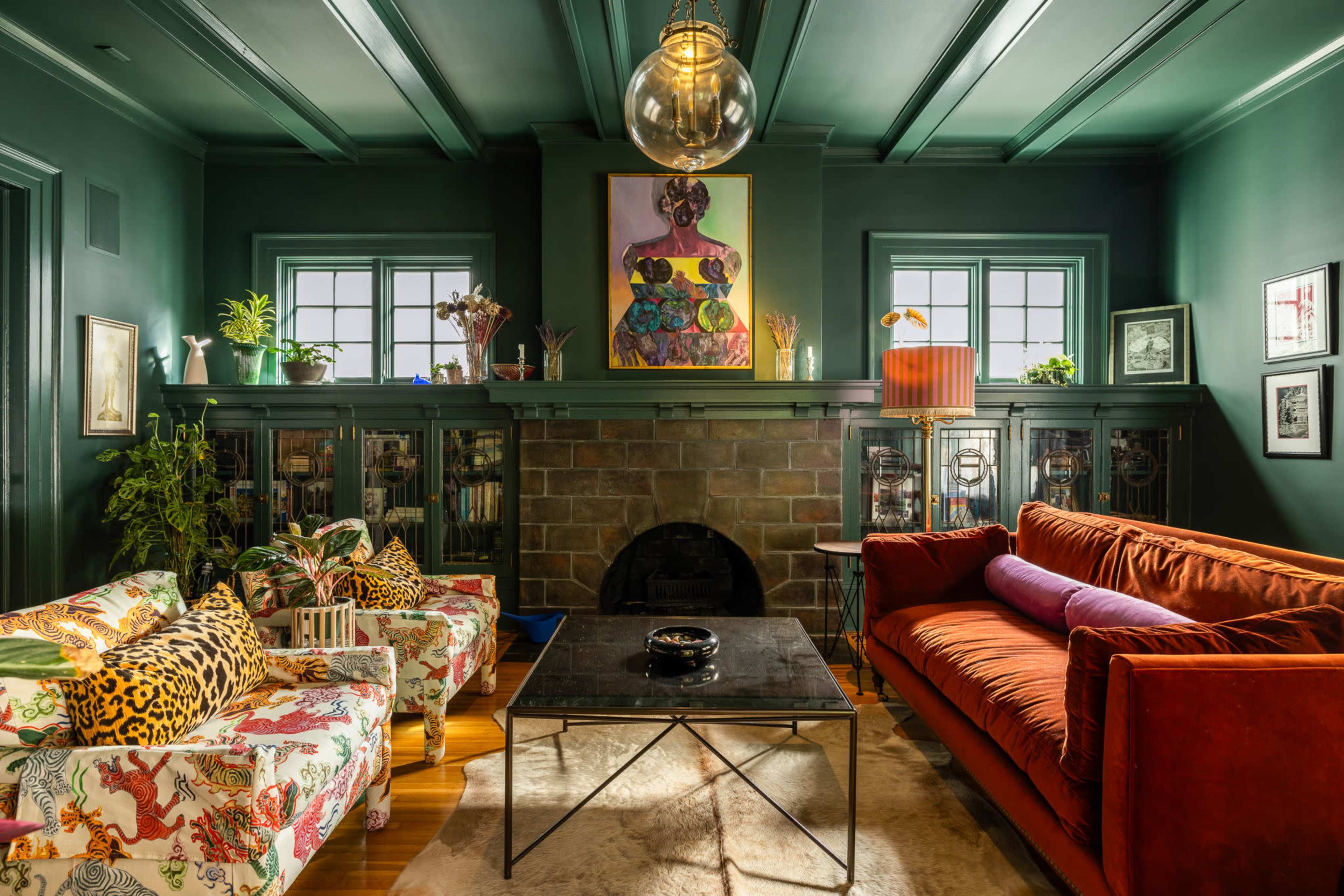 The image shows a stylized living room featuring a green ceiling, eclectic furniture, and decorative plants.