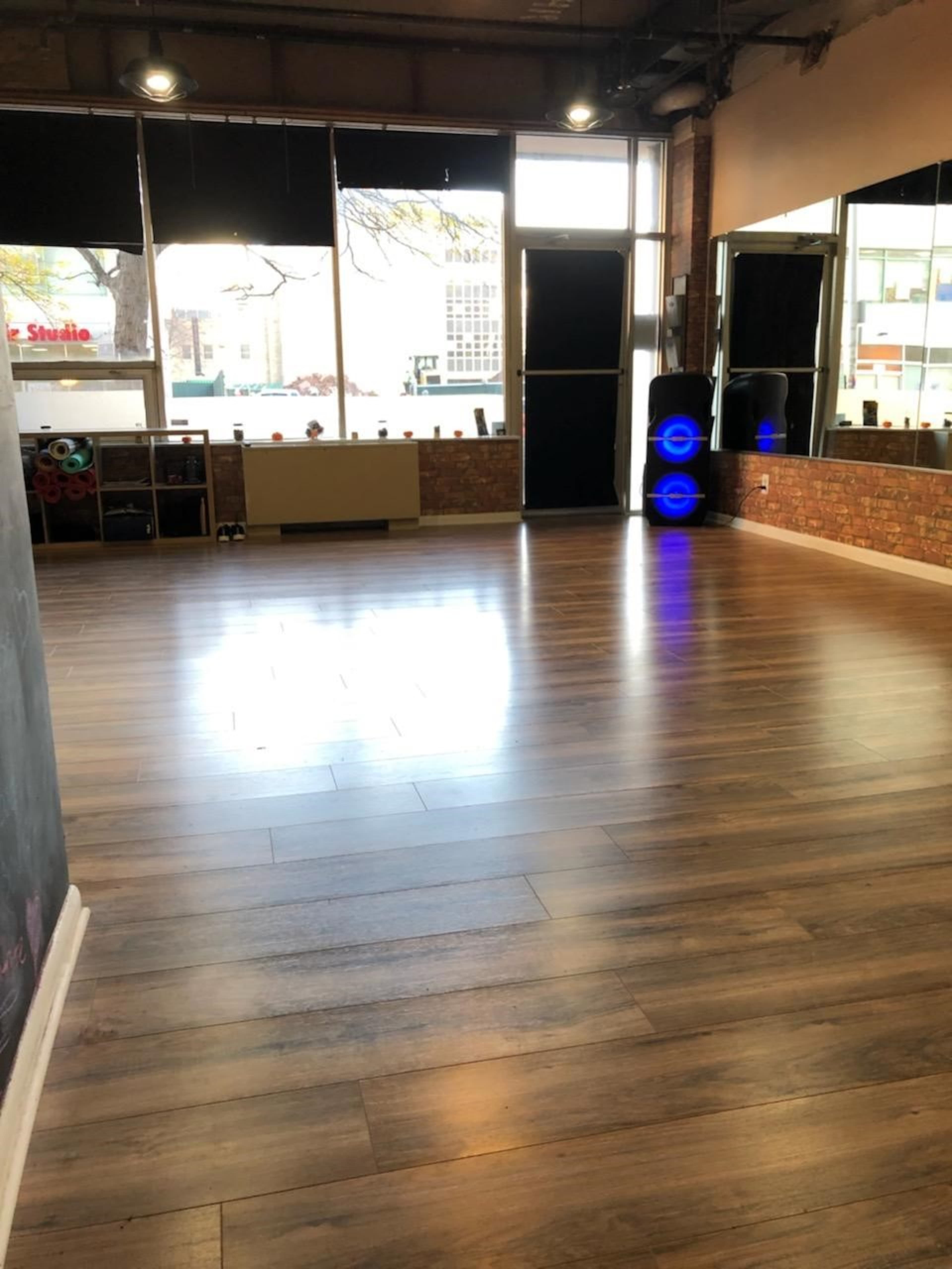 A spacious room with wooden floors, large windows, and a few pieces of exercise equipment against the wall.