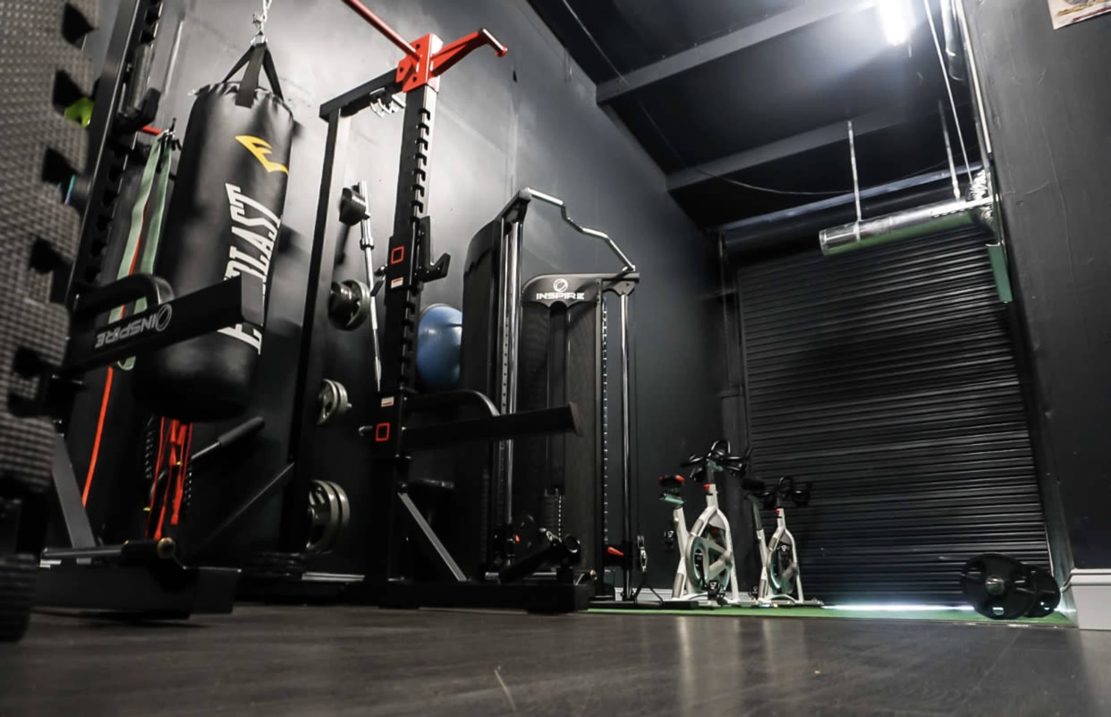 A fitness room featuring workout equipment, including a punching bag, weight rack, and exercise bikes.