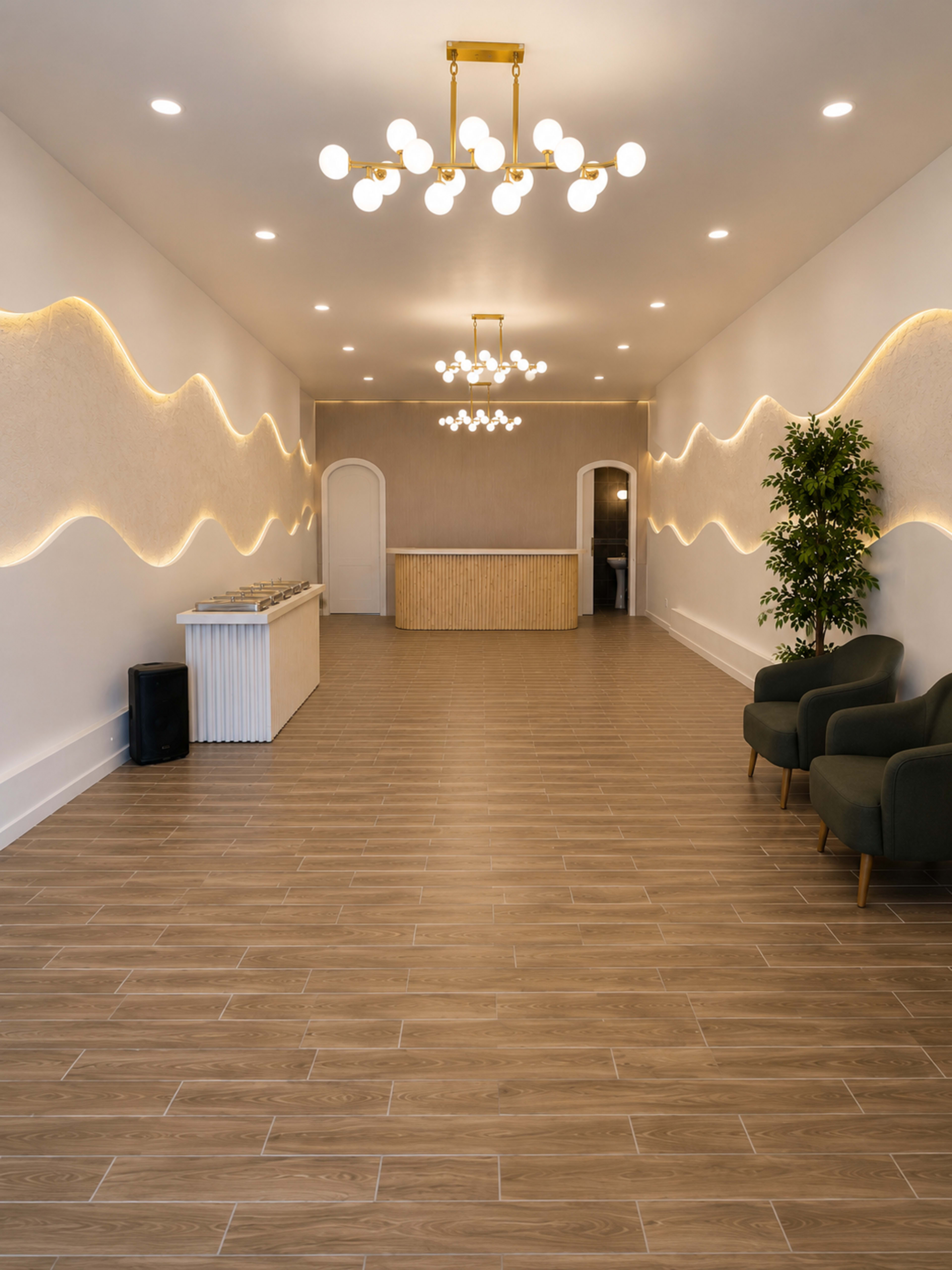 The interior of a spacious, modern reception area features a wooden check-in counter, two green armchairs, and soft, wavy lighting along the walls.