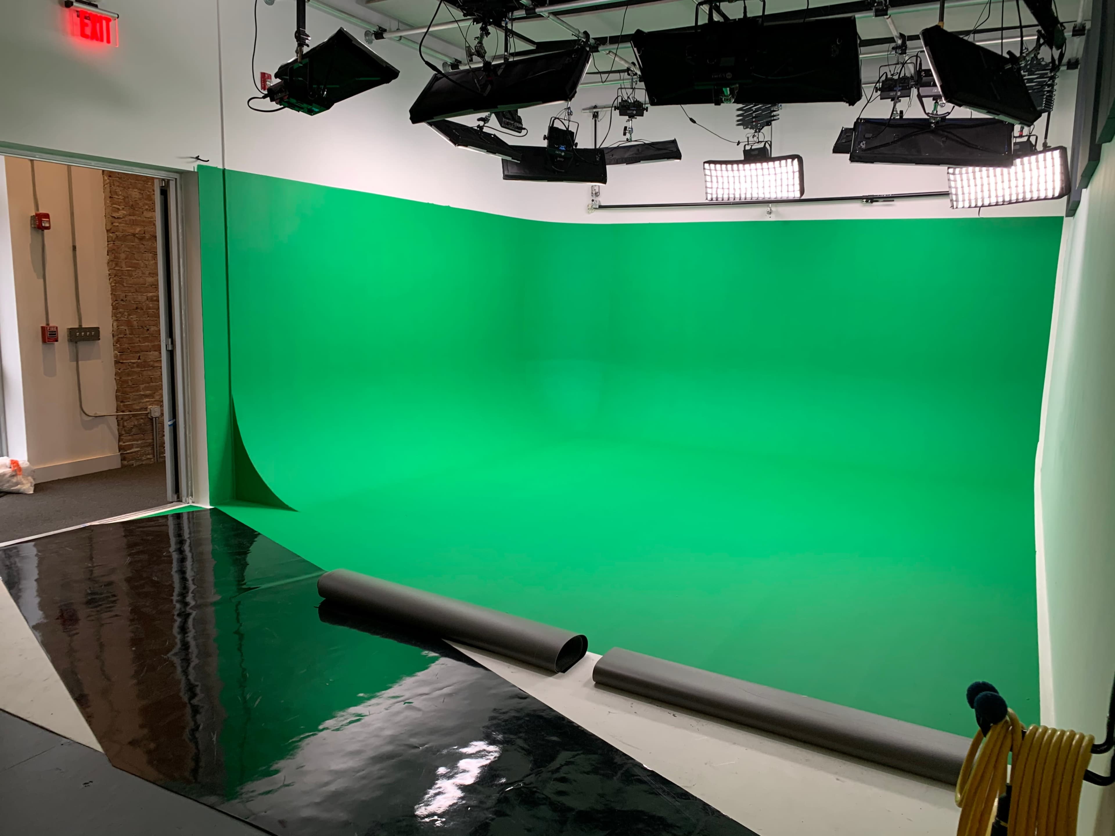 The image shows a green screen studio with bright lights and a smooth green backdrop.