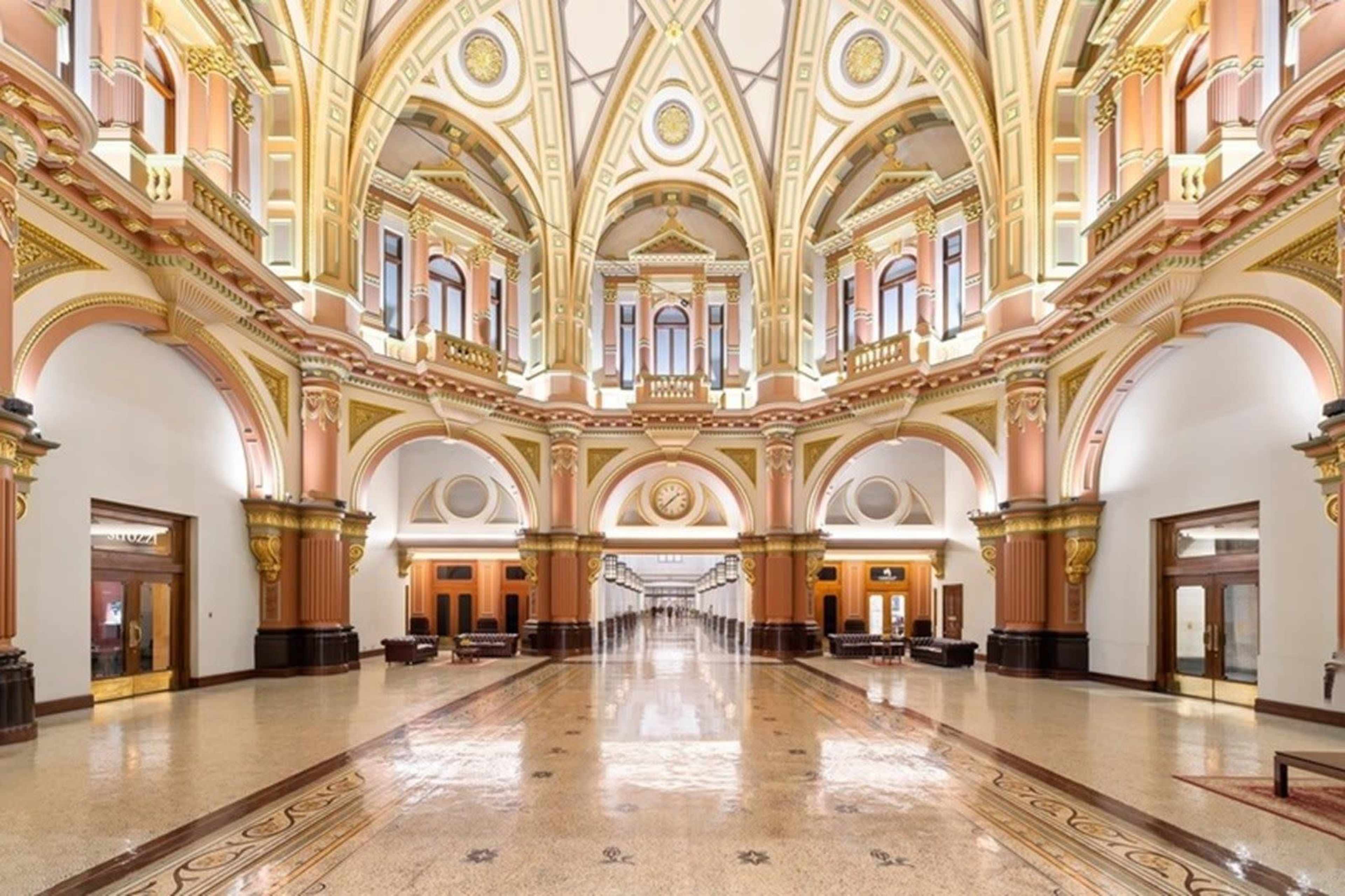 The image shows an ornate hall with a high, arched ceiling, intricate architectural details, and elegant furnishings.