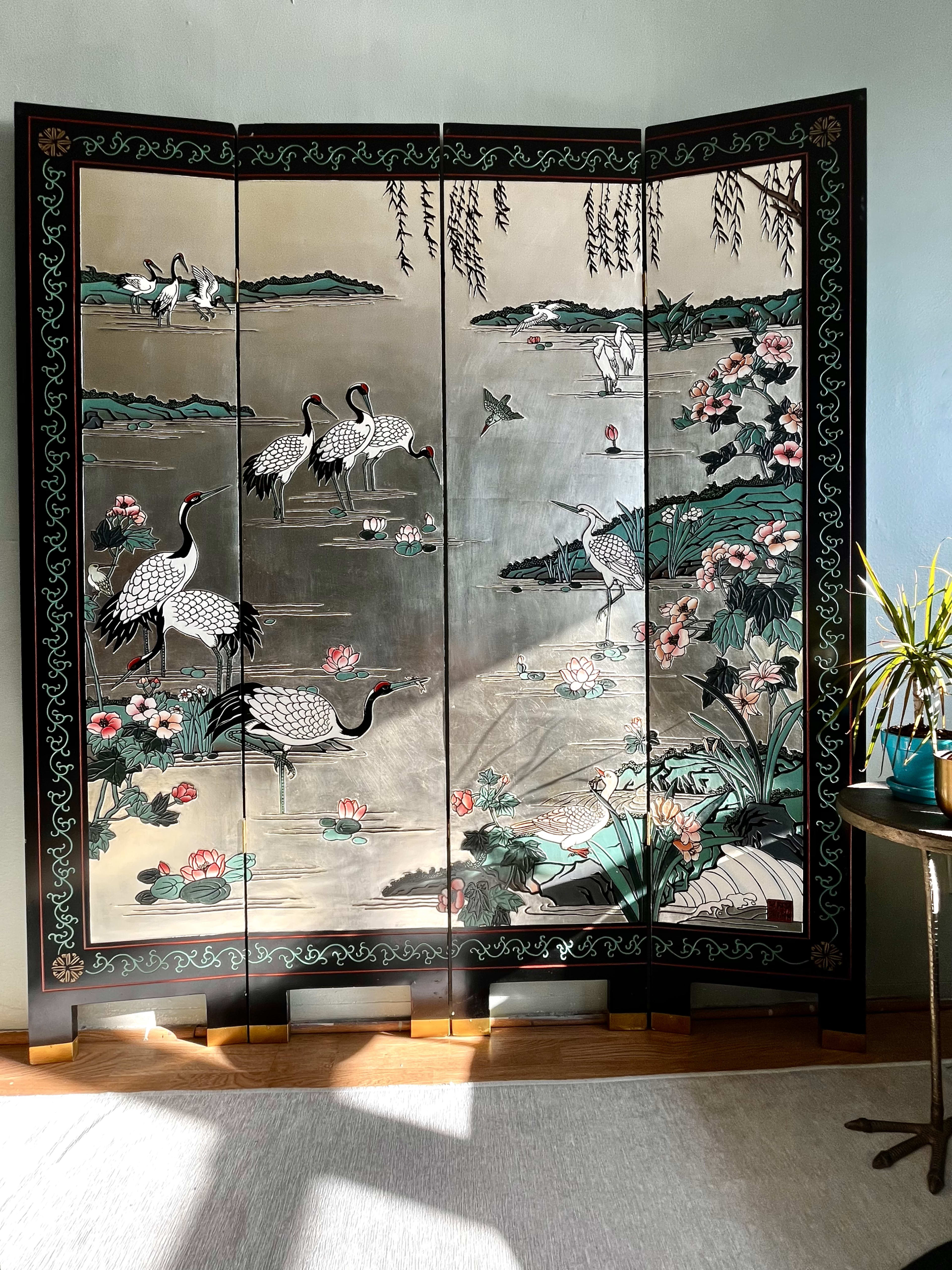 A decorative folding screen featuring herons and cranes amidst a landscape of water and blooming flowers.
