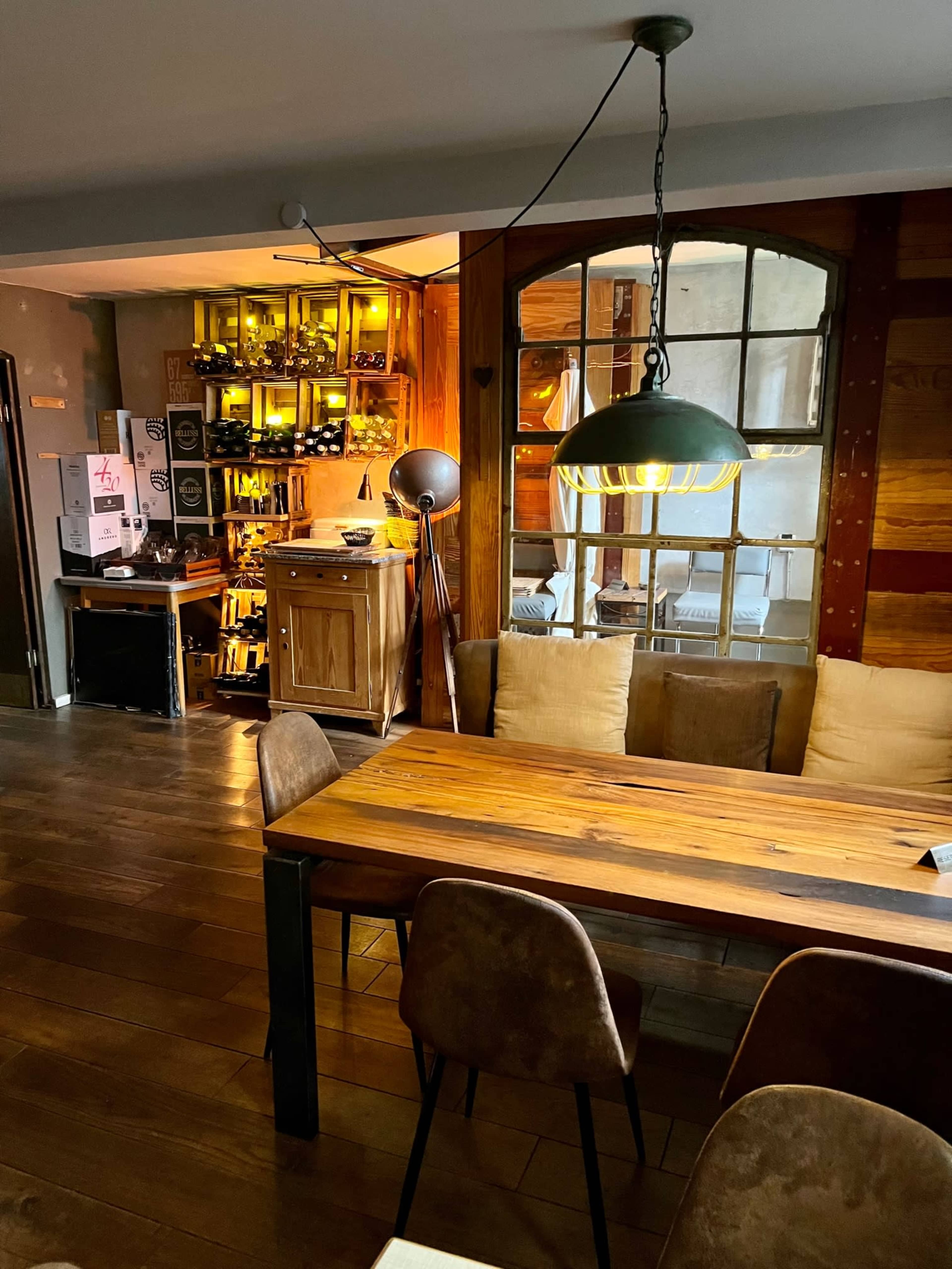 A cozy dining area with a wooden table, upholstered chairs, and a softly lit bar counter in the background.