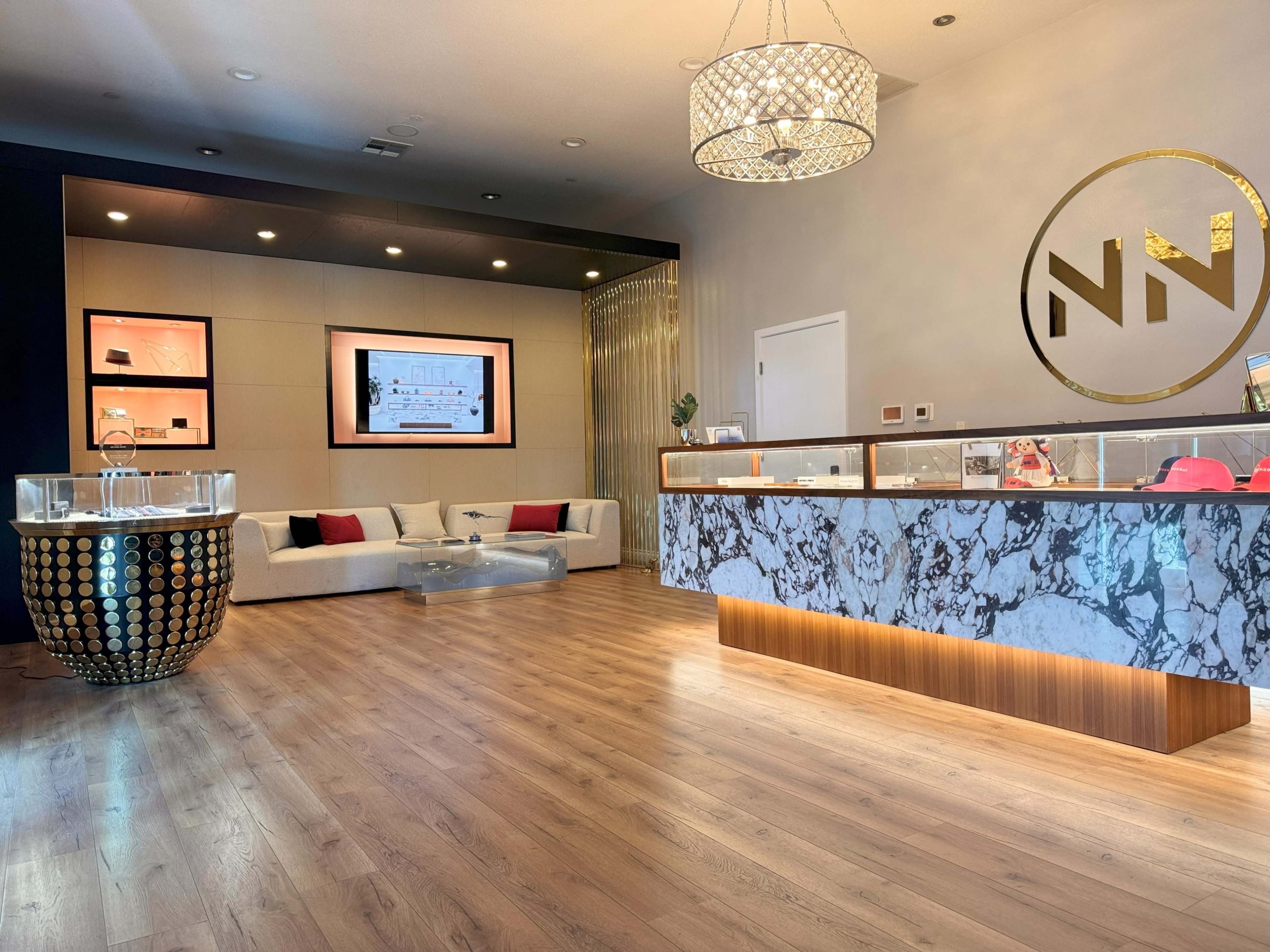 The image shows a modern reception area with a marble counter, a chic seating arrangement, and digital displays on the walls.