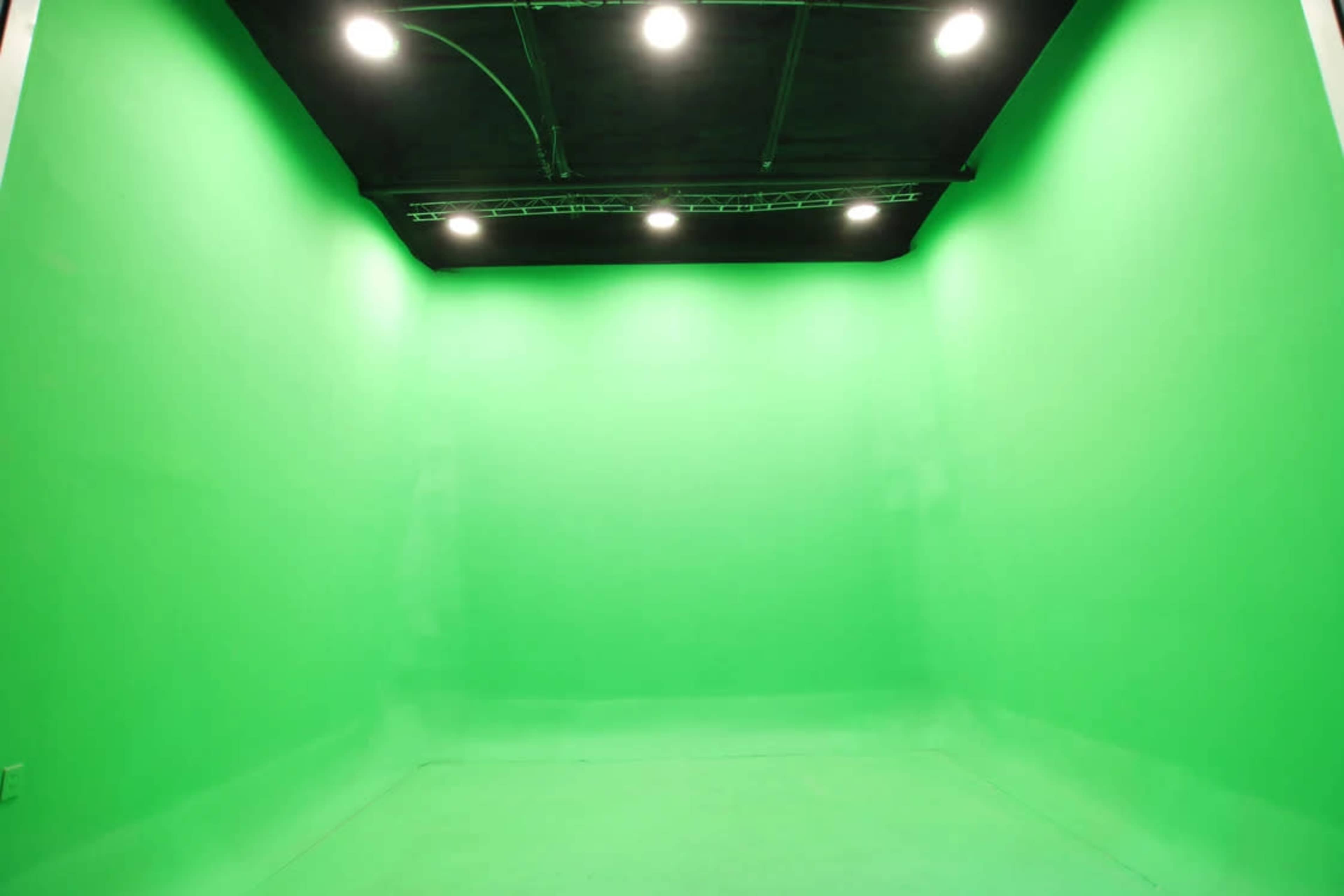 A green screen studio with bright lights attached to the ceiling.