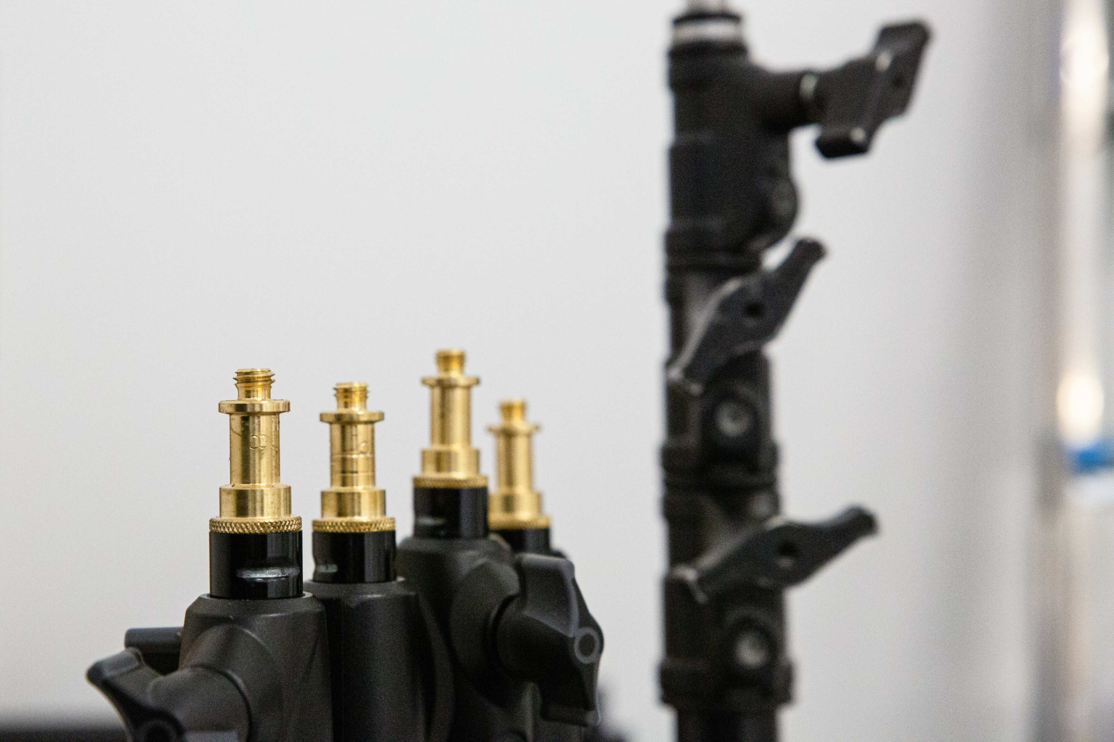 Several gold-colored valves mounted on a black base, with a multi-joint support structure in the background.