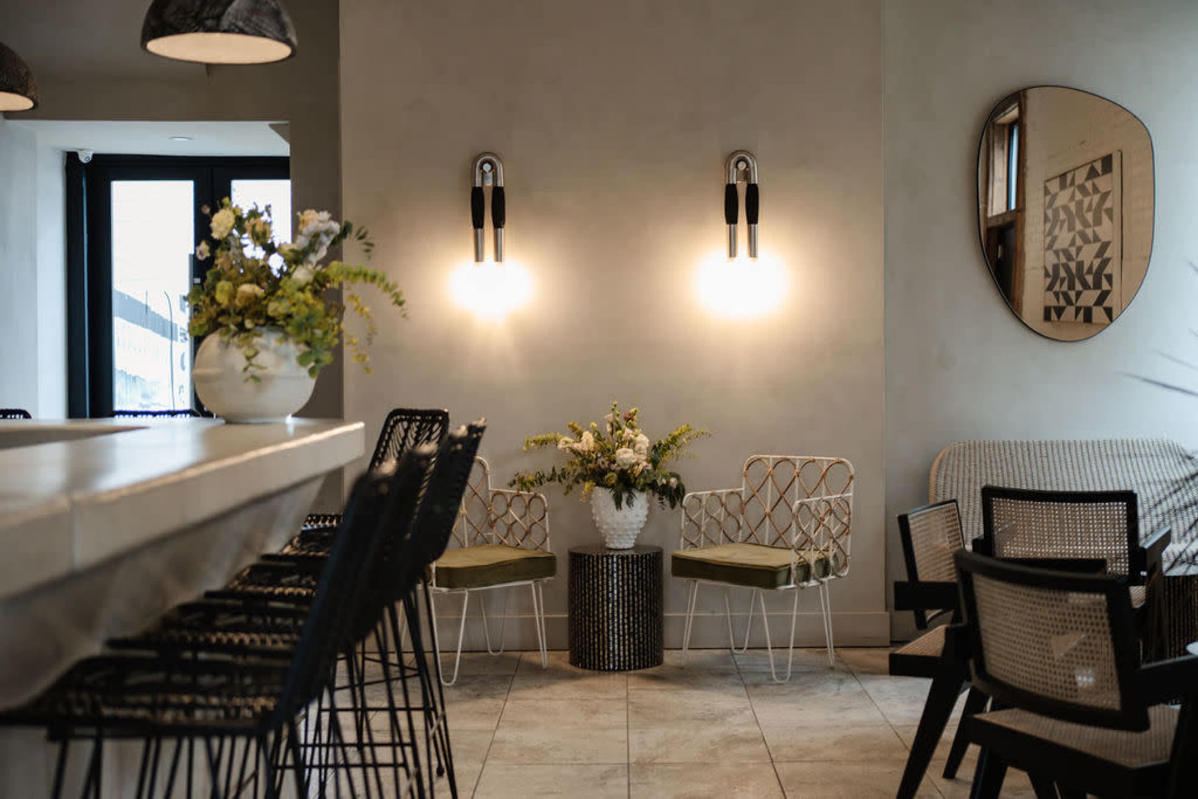 The image shows a modern interior space with a bar area, decorative wall lights, and a potted plant arrangement in a corner.
