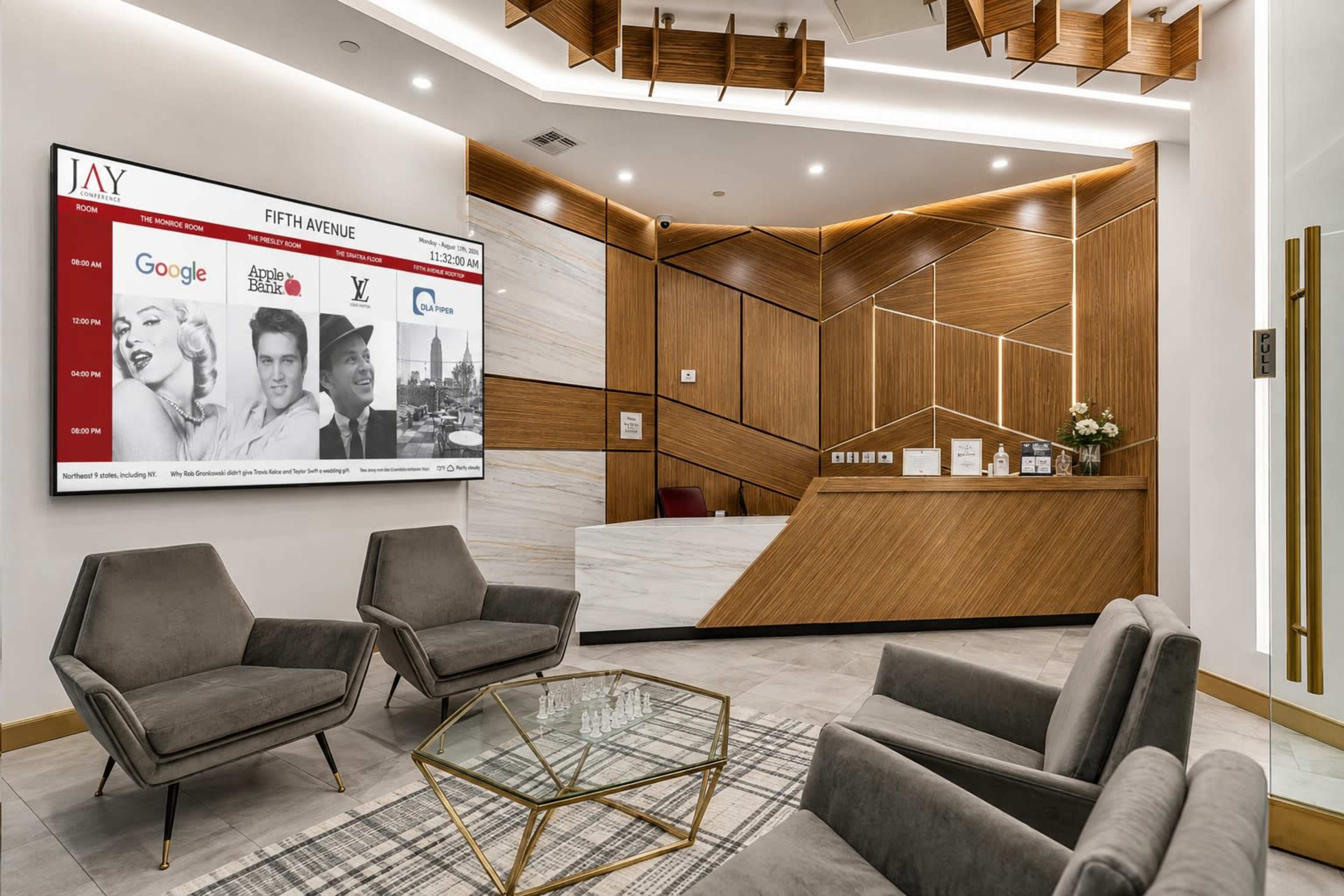 A modern reception area features elegant wooden accents, a large screen displaying brand logos, and plush seating arrangements.