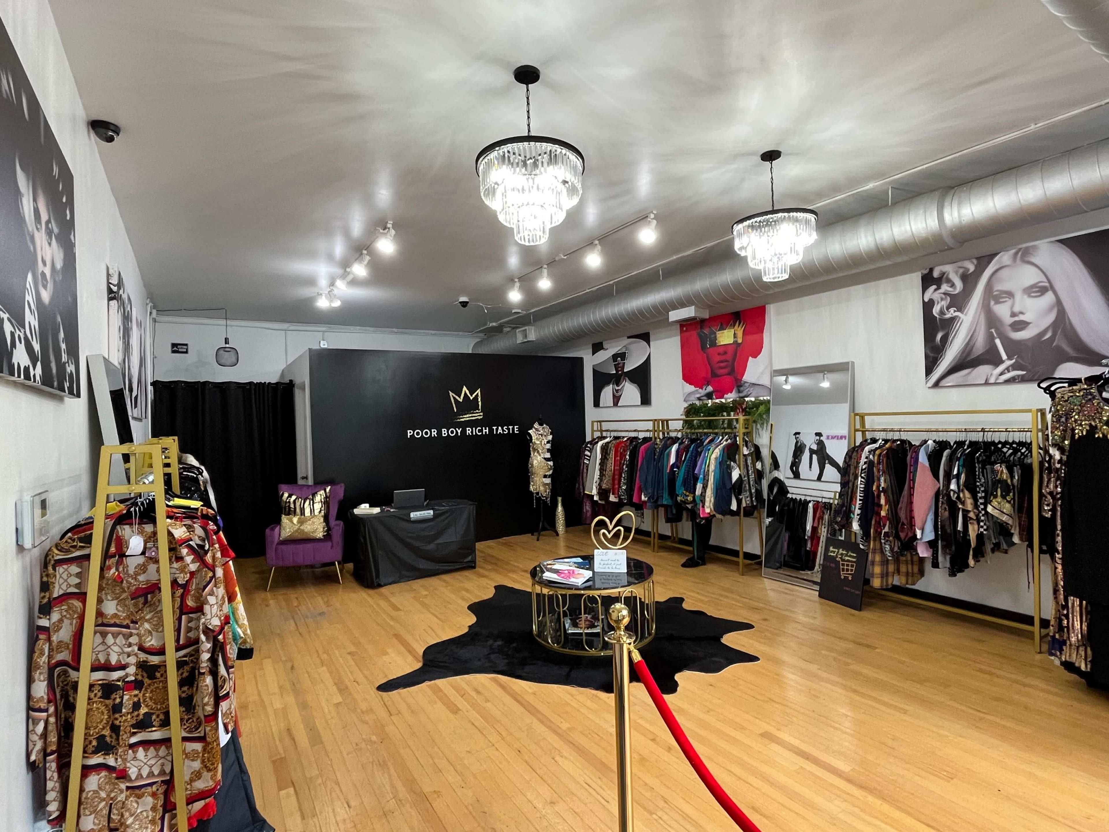 The image shows a boutique interior featuring racks of clothing, a central table, and large fashion-themed wall art.
