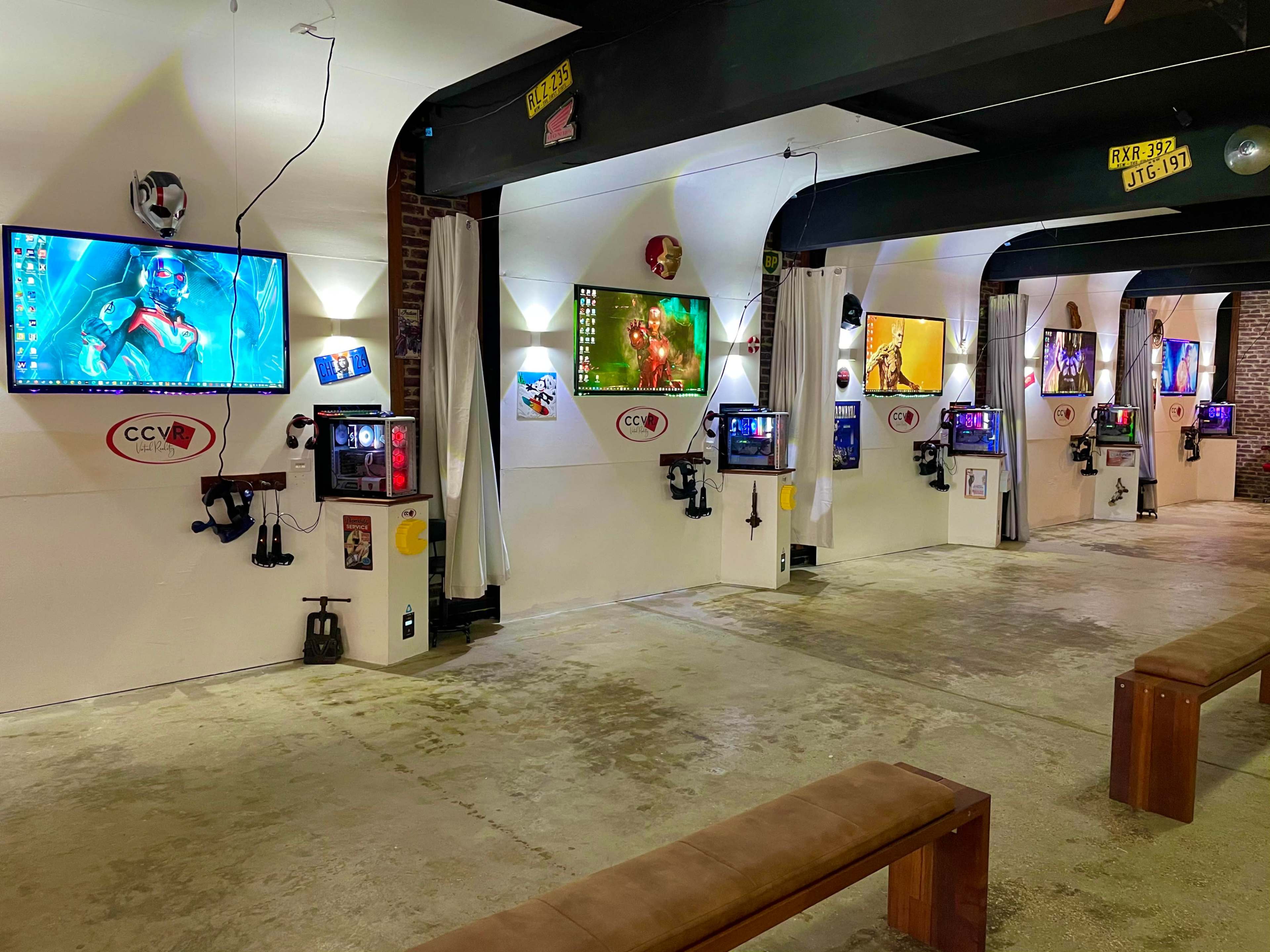 A modern gallery space with multiple computer monitors displaying vibrant artwork mounted on white walls, paired with various gaming consoles and accessories.