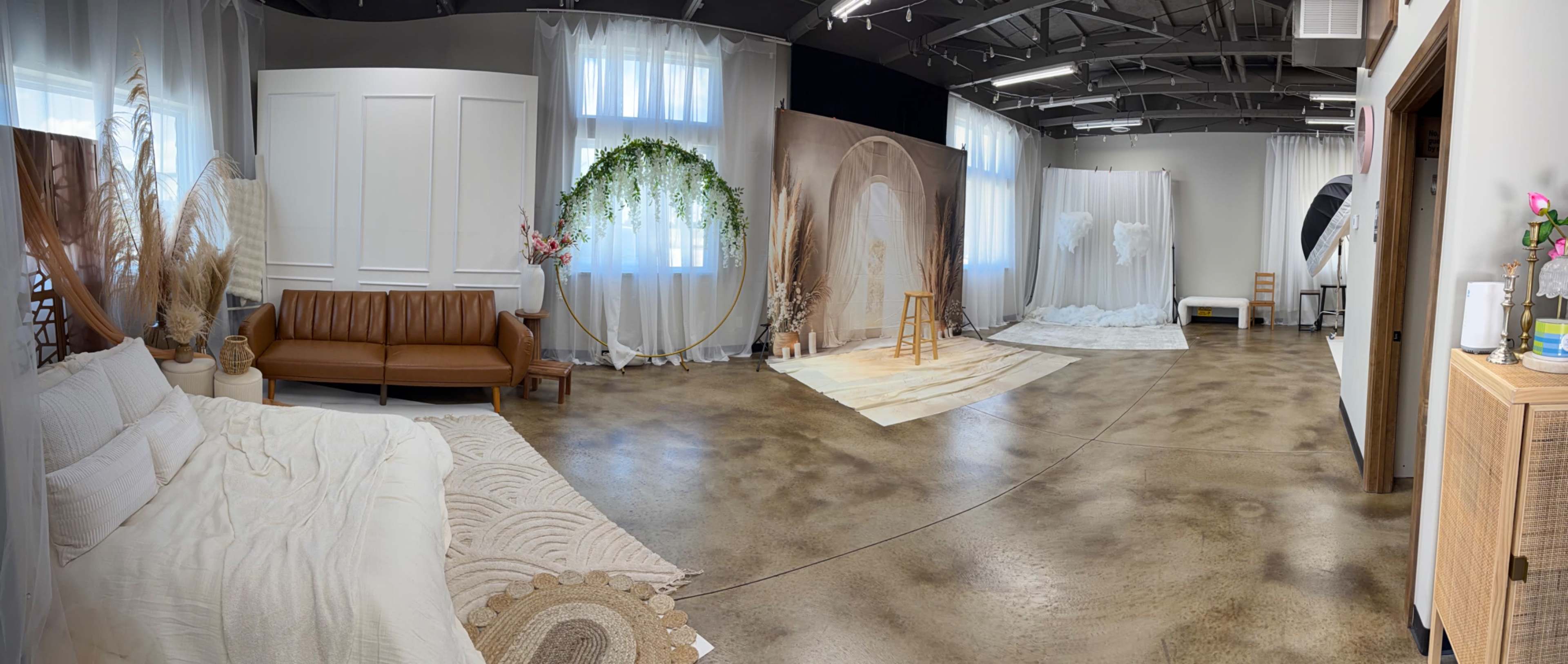 The image shows an interior studio space with various backdrops, a brown couch, and a wooden stool, arranged for photography sessions.