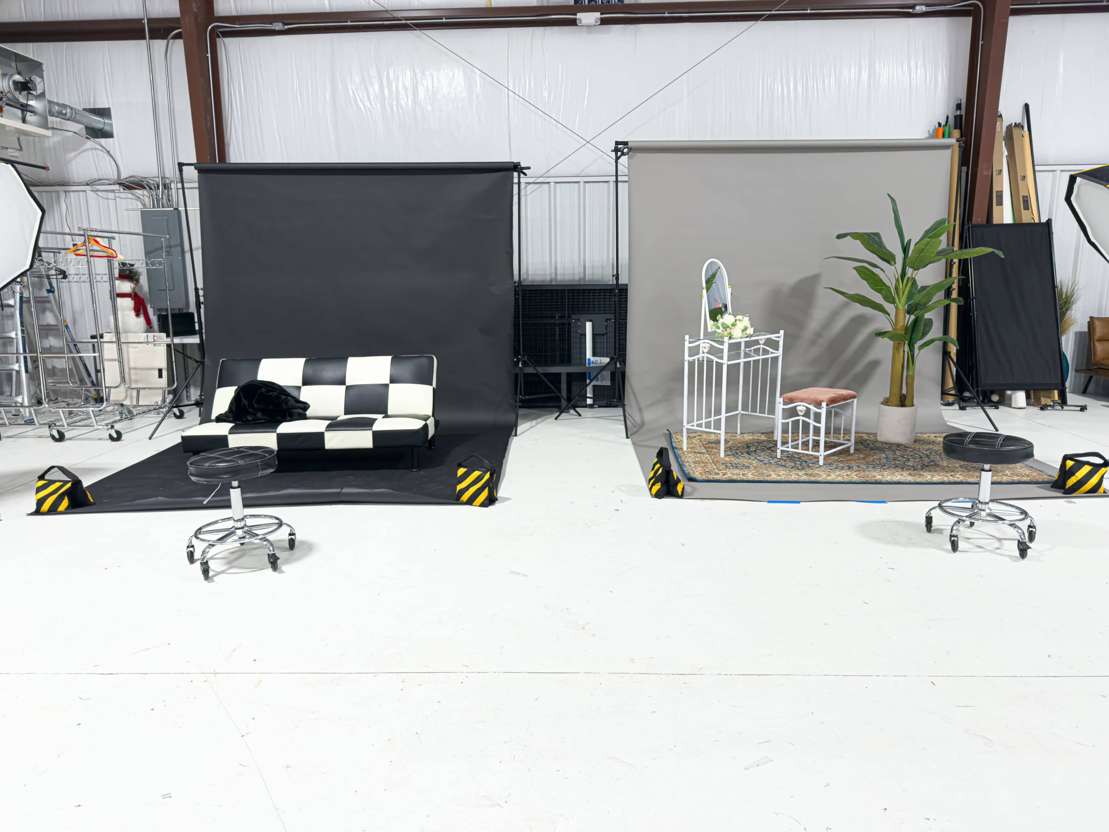 The image shows a photography studio setup with two distinct scenes: one featuring a black and white checkered couch and the other displaying a plant next to a white mirror and a small chair on a patterned rug.