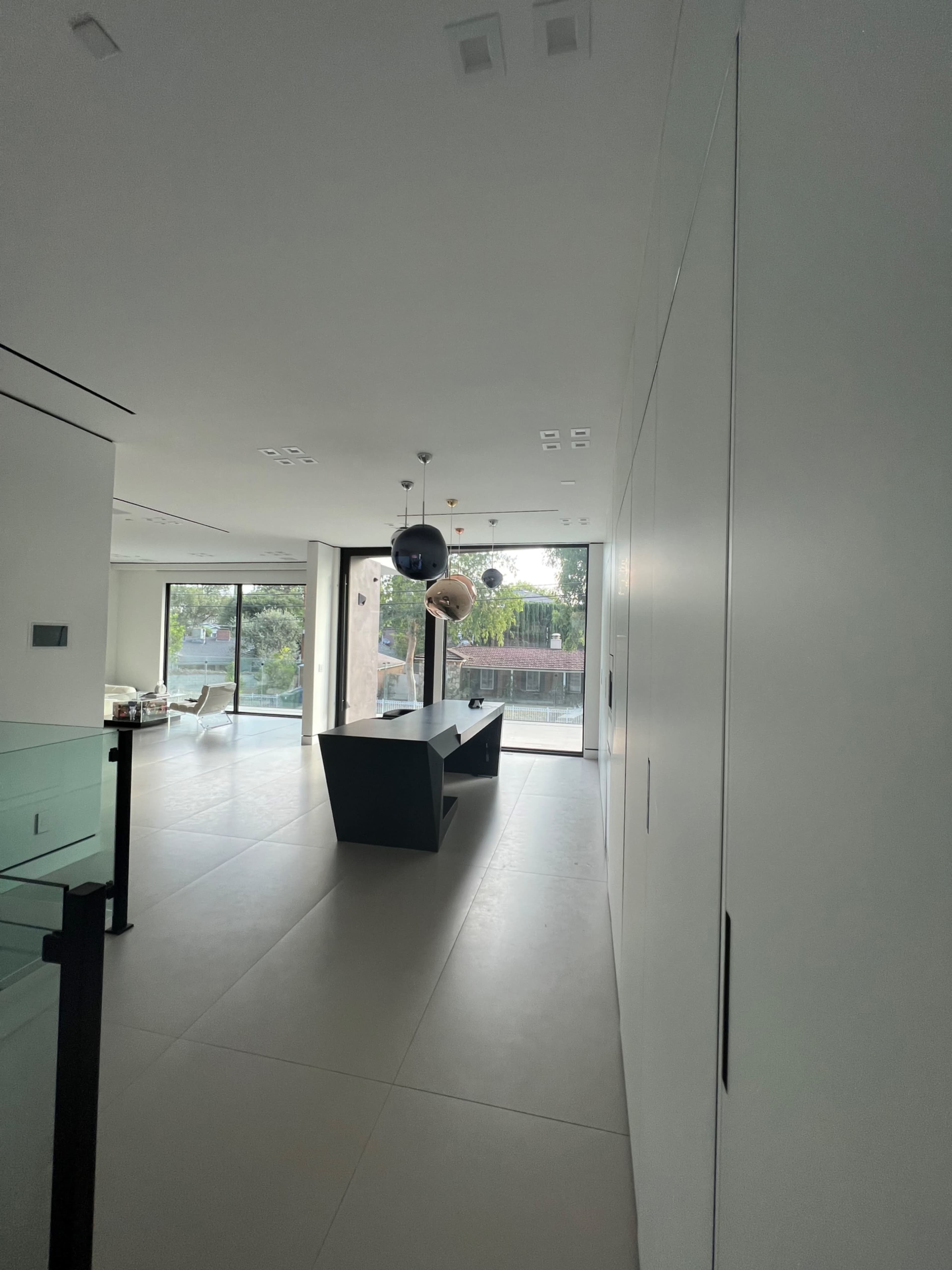 A modern interior space with minimalistic design, featuring a dark countertop island and large windows that allow natural light to enter.