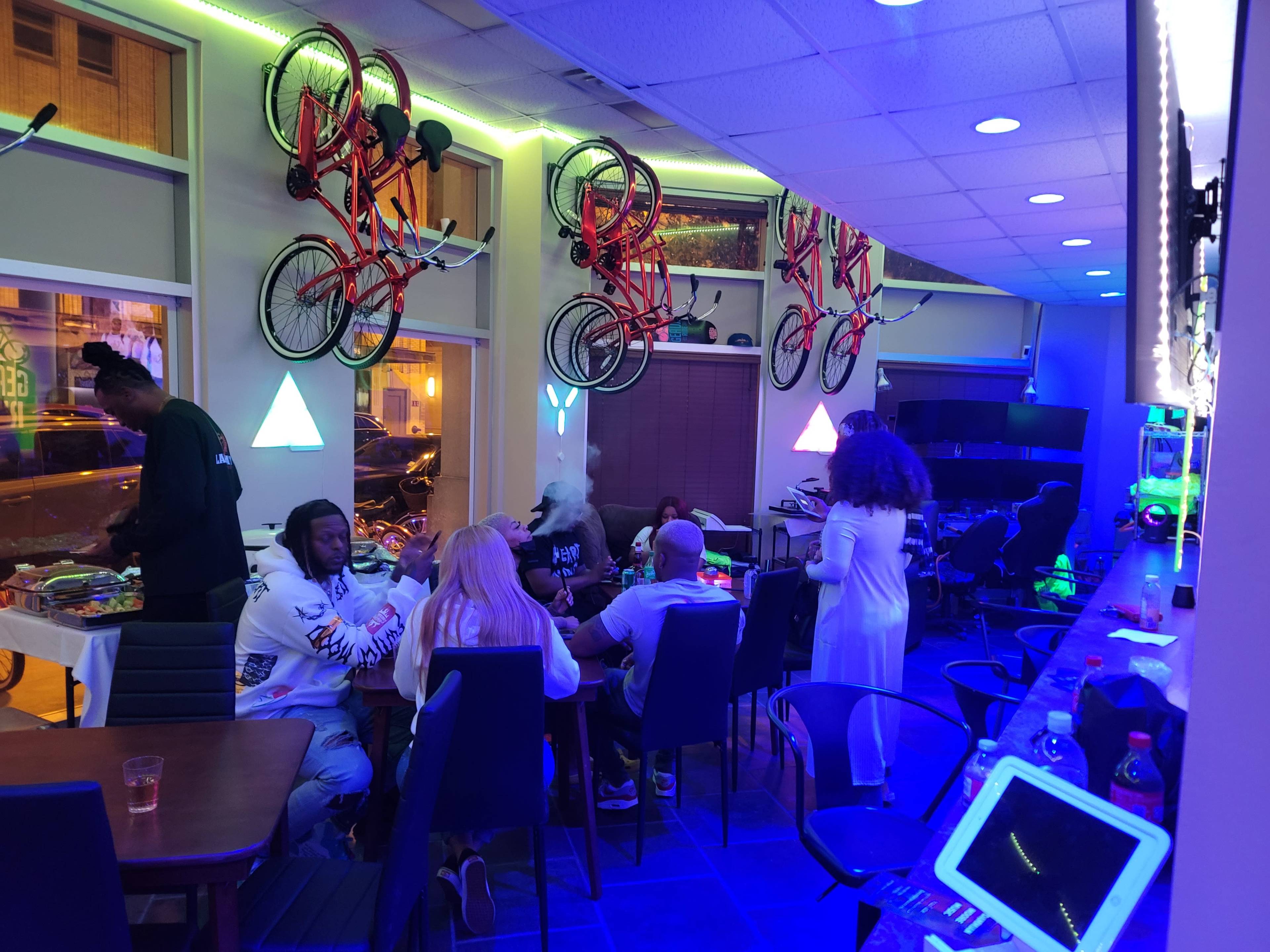 A group of people gather around a table in a brightly lit room adorned with bicycles mounted on the walls.