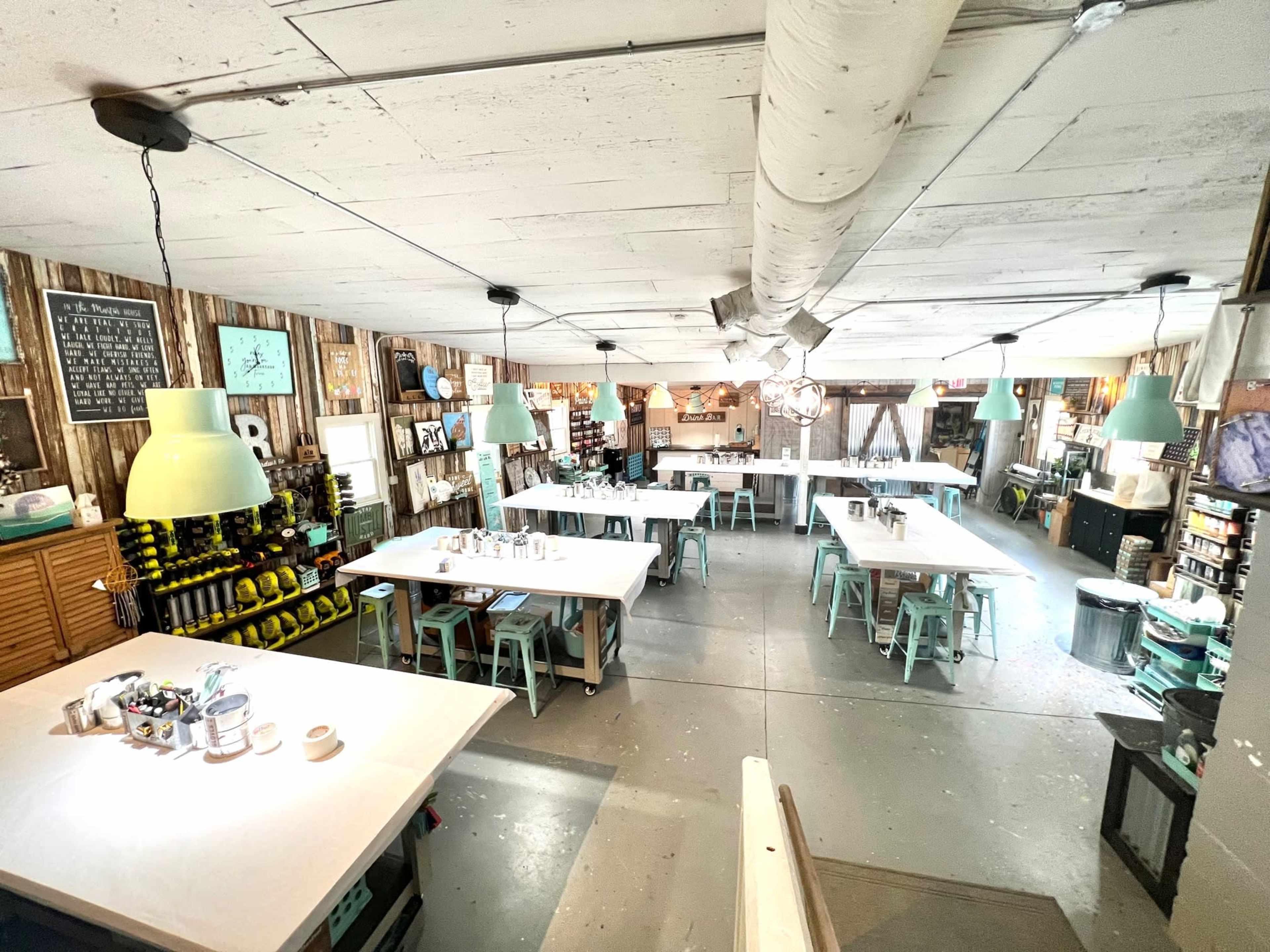 A spacious, well-lit room set up for a workshop, featuring multiple tables and stools organized in a grid pattern.