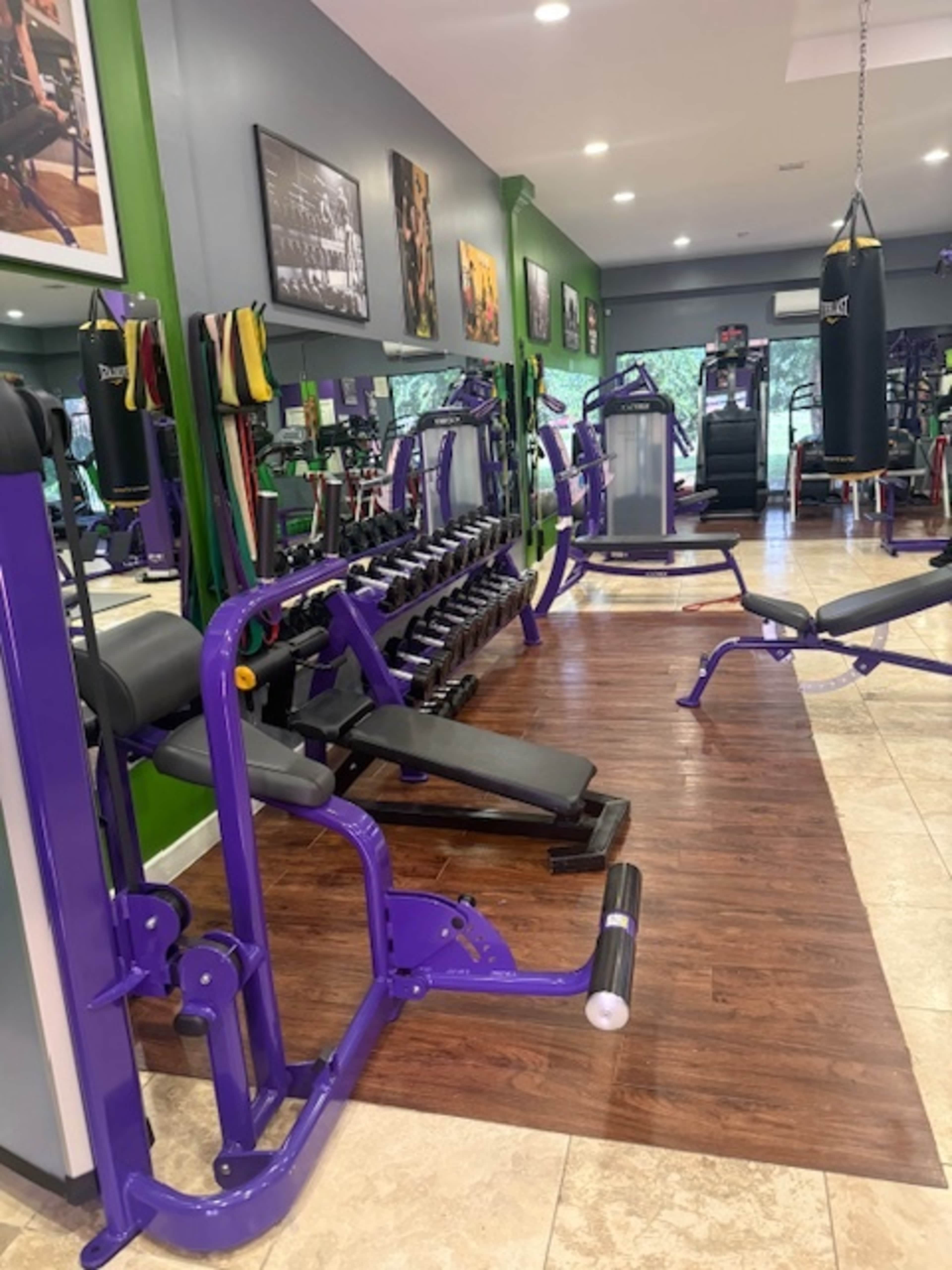 The image shows a gym interior featuring various exercise machines, free weights, and a punching bag in a well-lit environment.