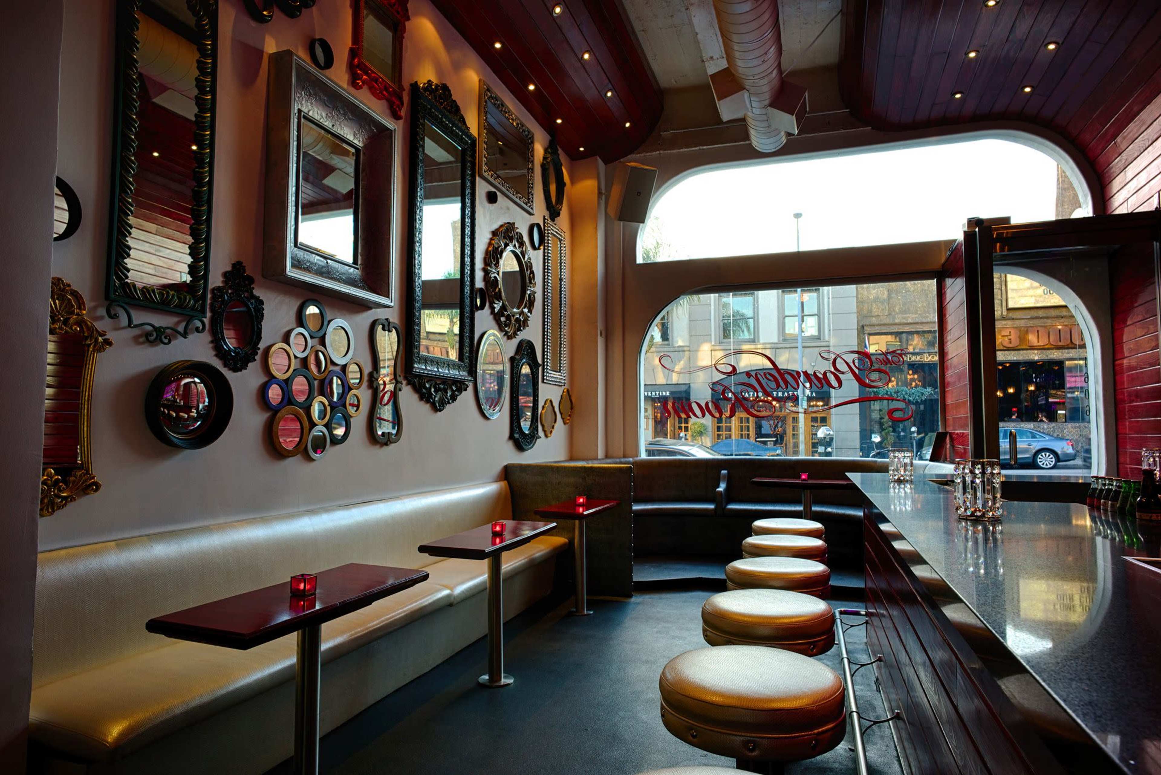 A bar interior with a curved, wooden counter, several circular mirrors on the wall, and seating along a beige booth.