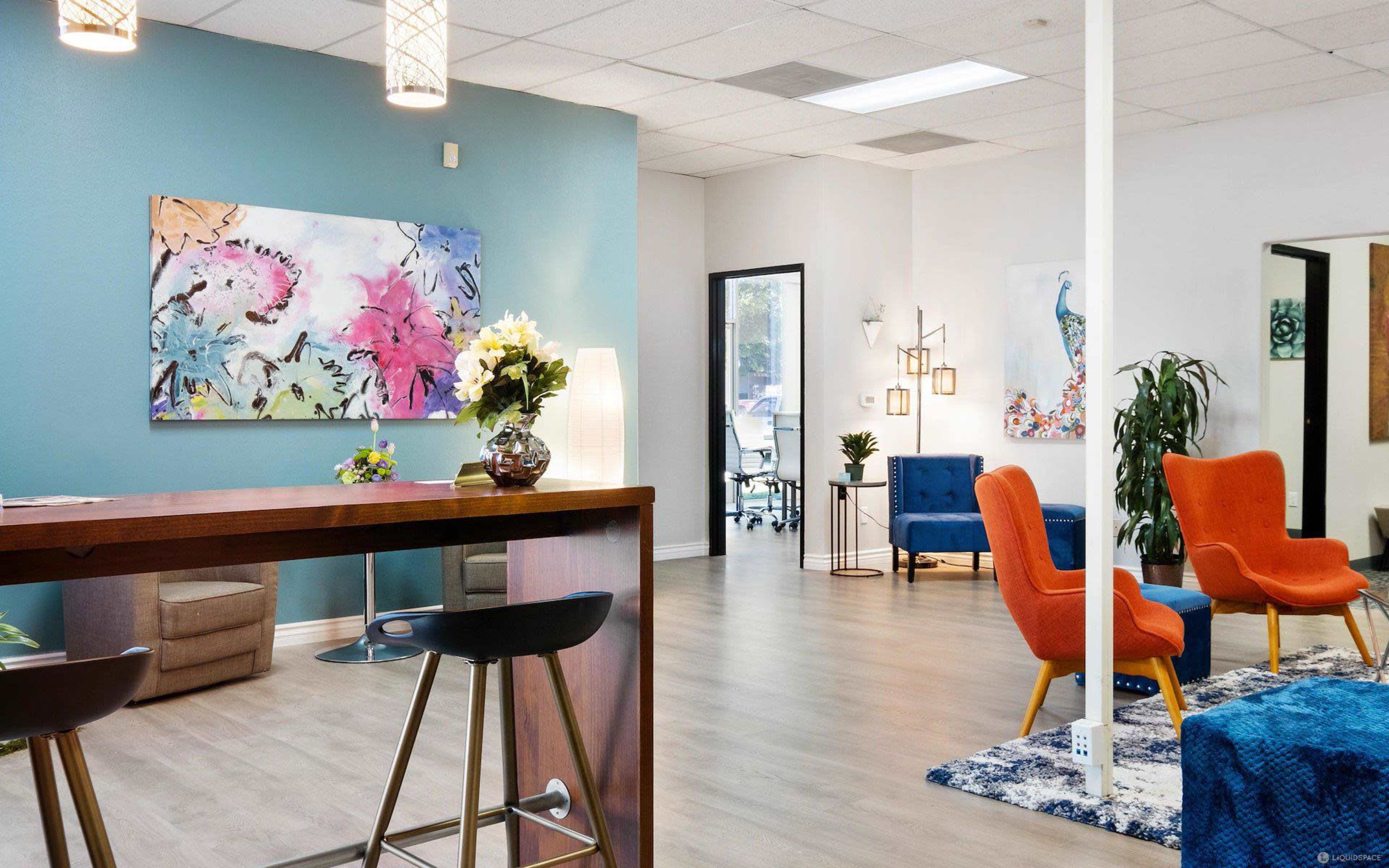 A modern waiting area with colorful artwork, comfortable seating, and a reception desk.